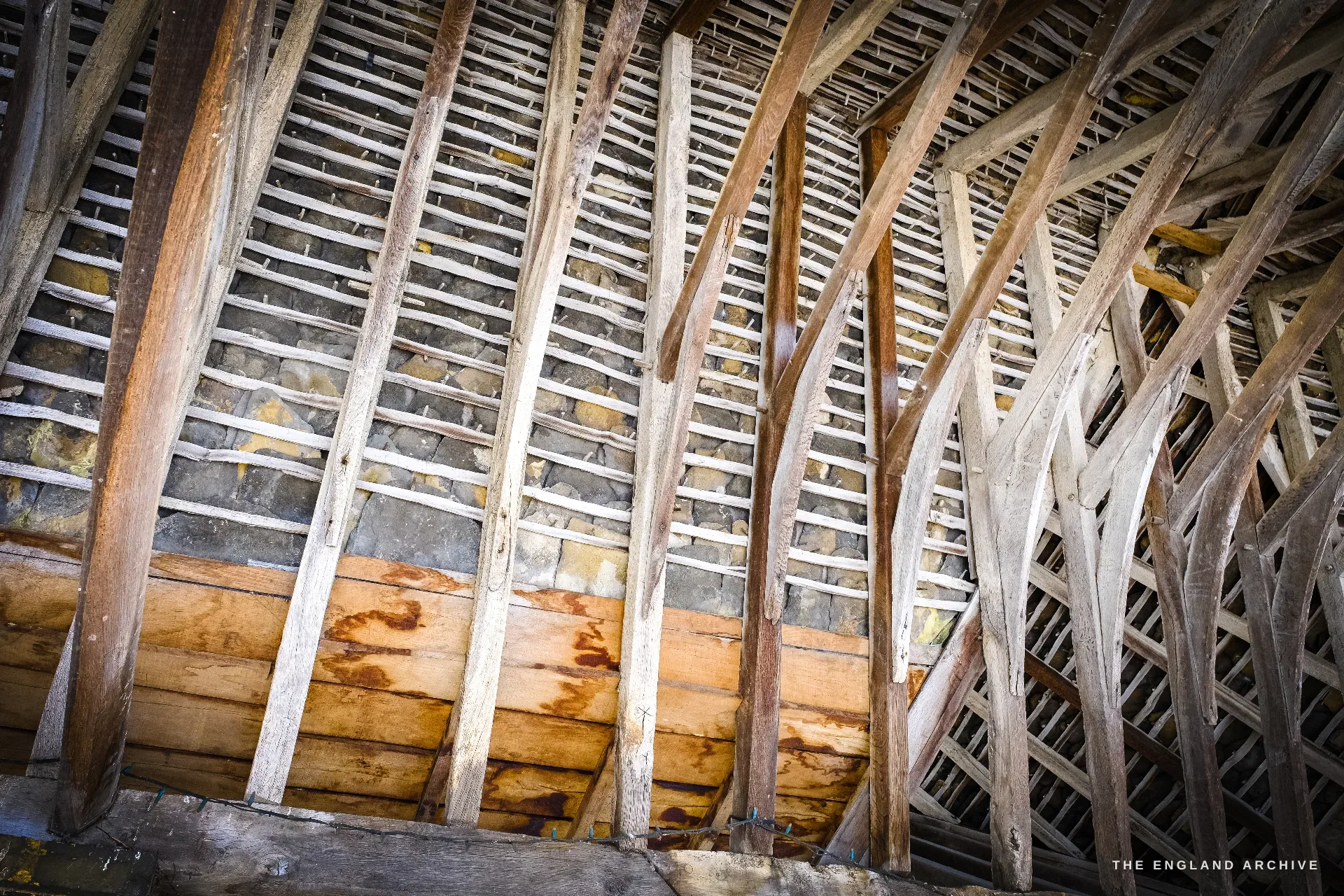 Looking up into the Market Hall roof - exposed timber trusses, rafters and laths with stone rubble infill between.