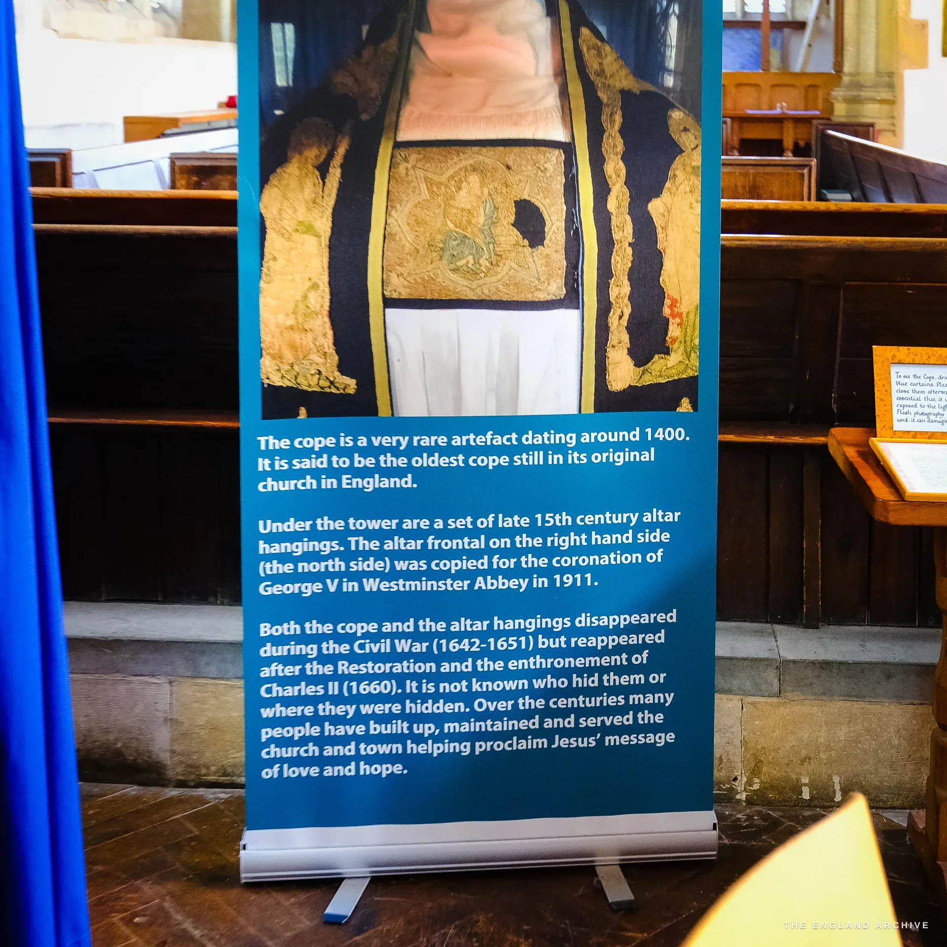 Close on the pull-up banner in St James' Church showing the gold-embroidered cope and the text explaining that it dates from around 1400 and is the oldest cope still in its original church in England.
