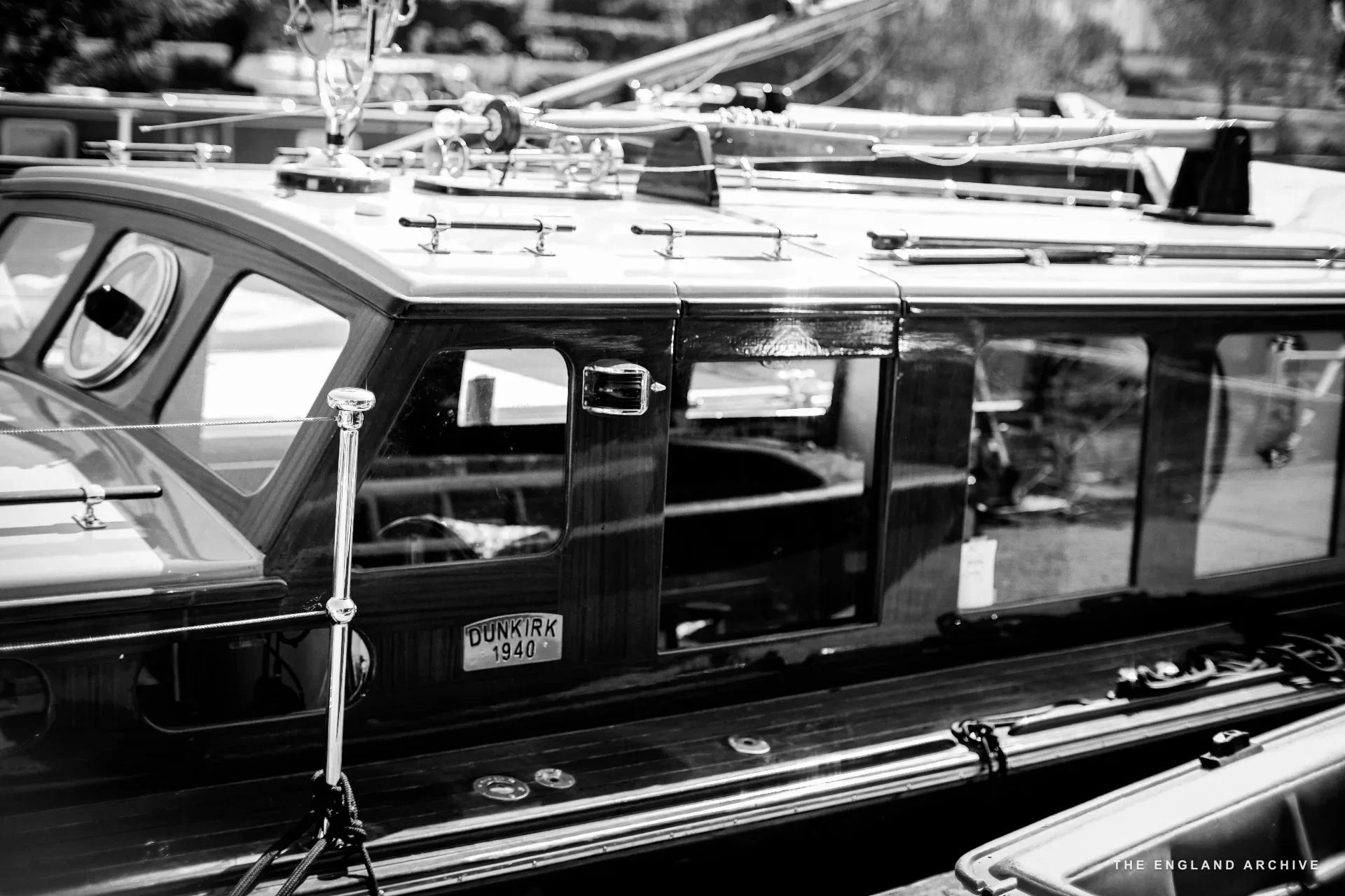 A close view of the cabin of a Little Ship of Dunkirk in the yard, the brass DUNKIRK 1940 plaque mounted on the cabin wall.