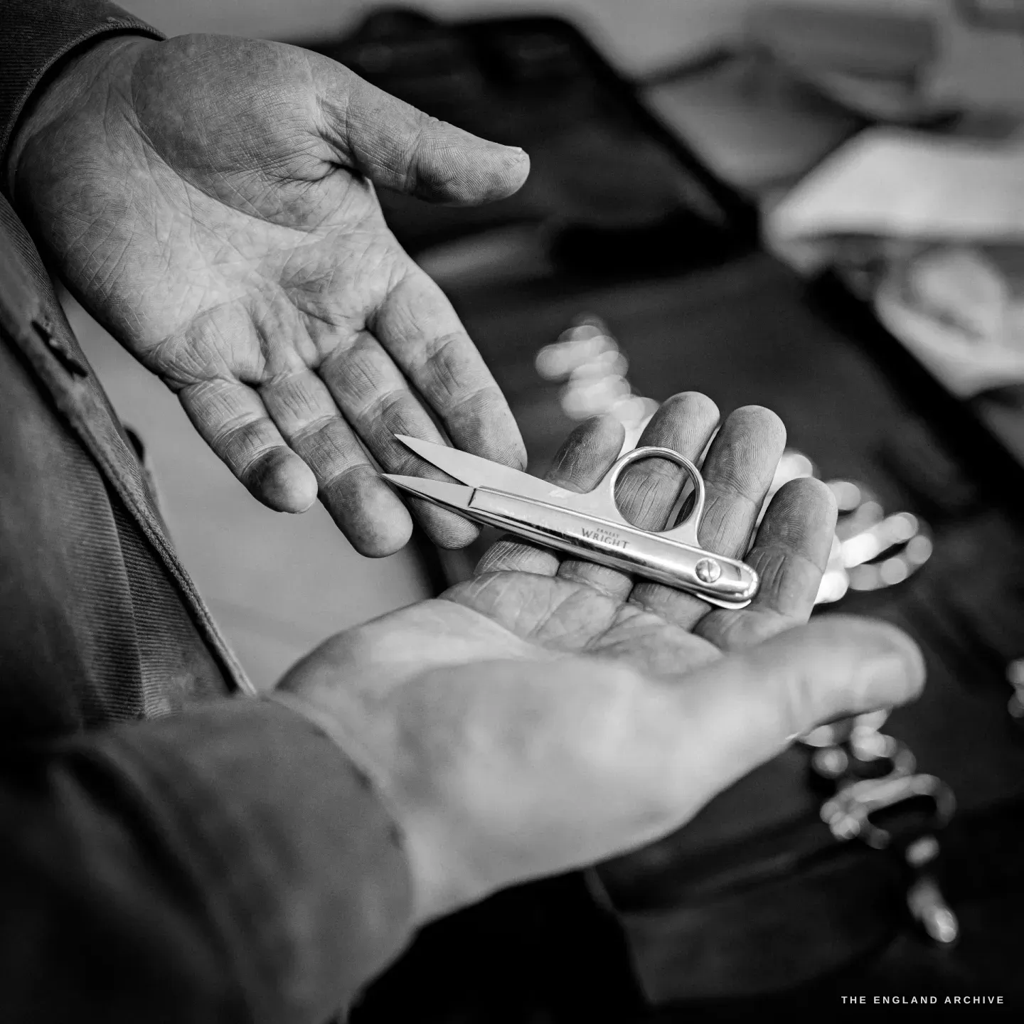 A small pair of spring-bow thread nips resting across an open palm, the WRIGHT name etched on the short blade.