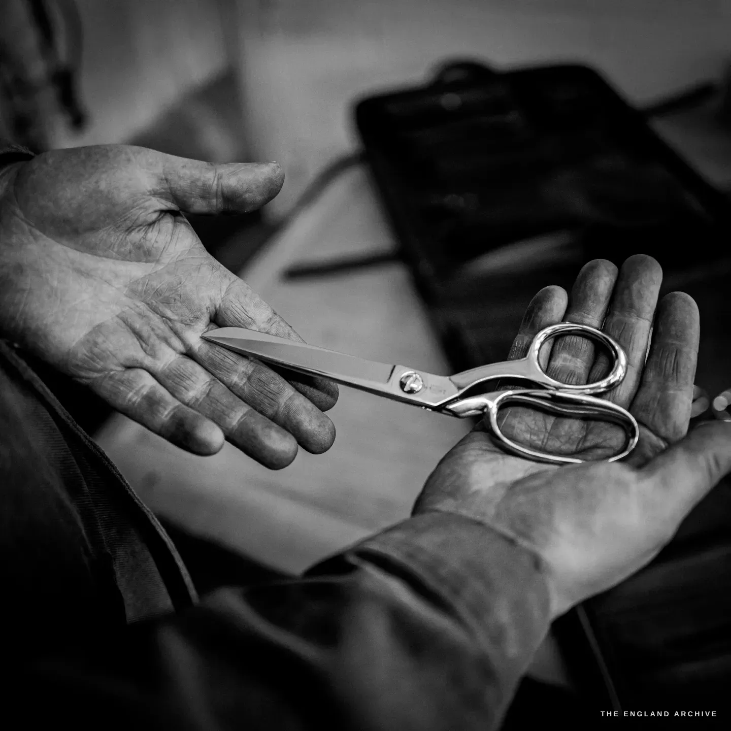 A pair of straight household scissors resting across an open palm, etched WRIGHT at the blade.