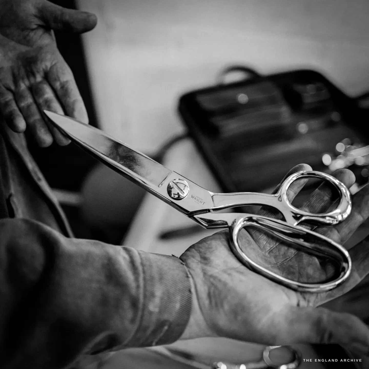 A pair of dressmaker's shears with a cranked, offset handle held in a maker's hands, etched ERNEST WRIGHT.
