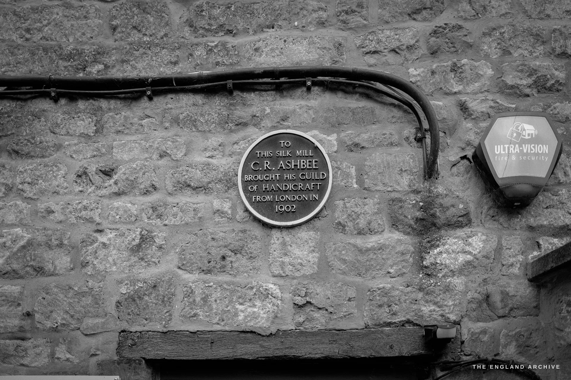 A close study of the round commemorative plaque on the Silk Mill's rubble-stone wall recording that C. R. Ashbee brought his Guild of Handicraft here from London in 1902.