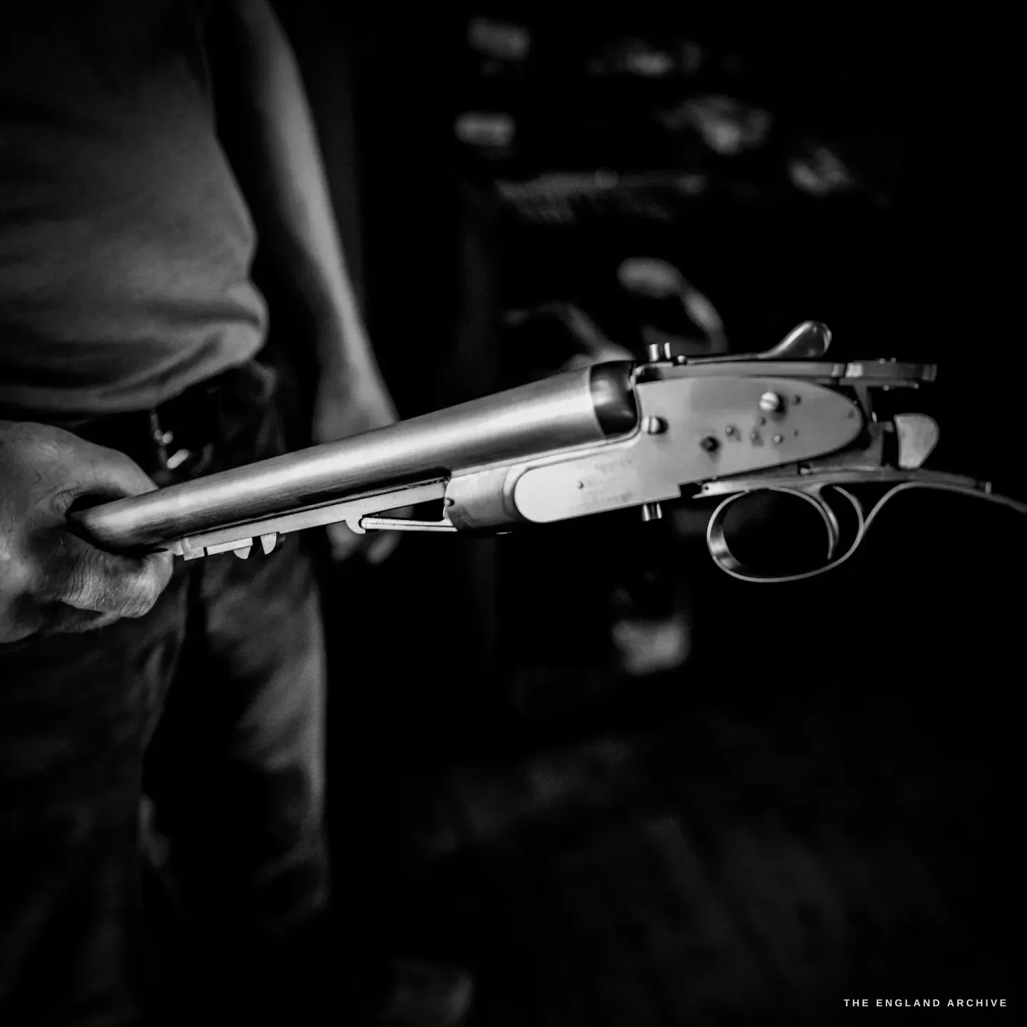 Haydn Hill's hands hold a shotgun action and trigger plate in the white - bright unfinished steel - the fitted lockwork showing.