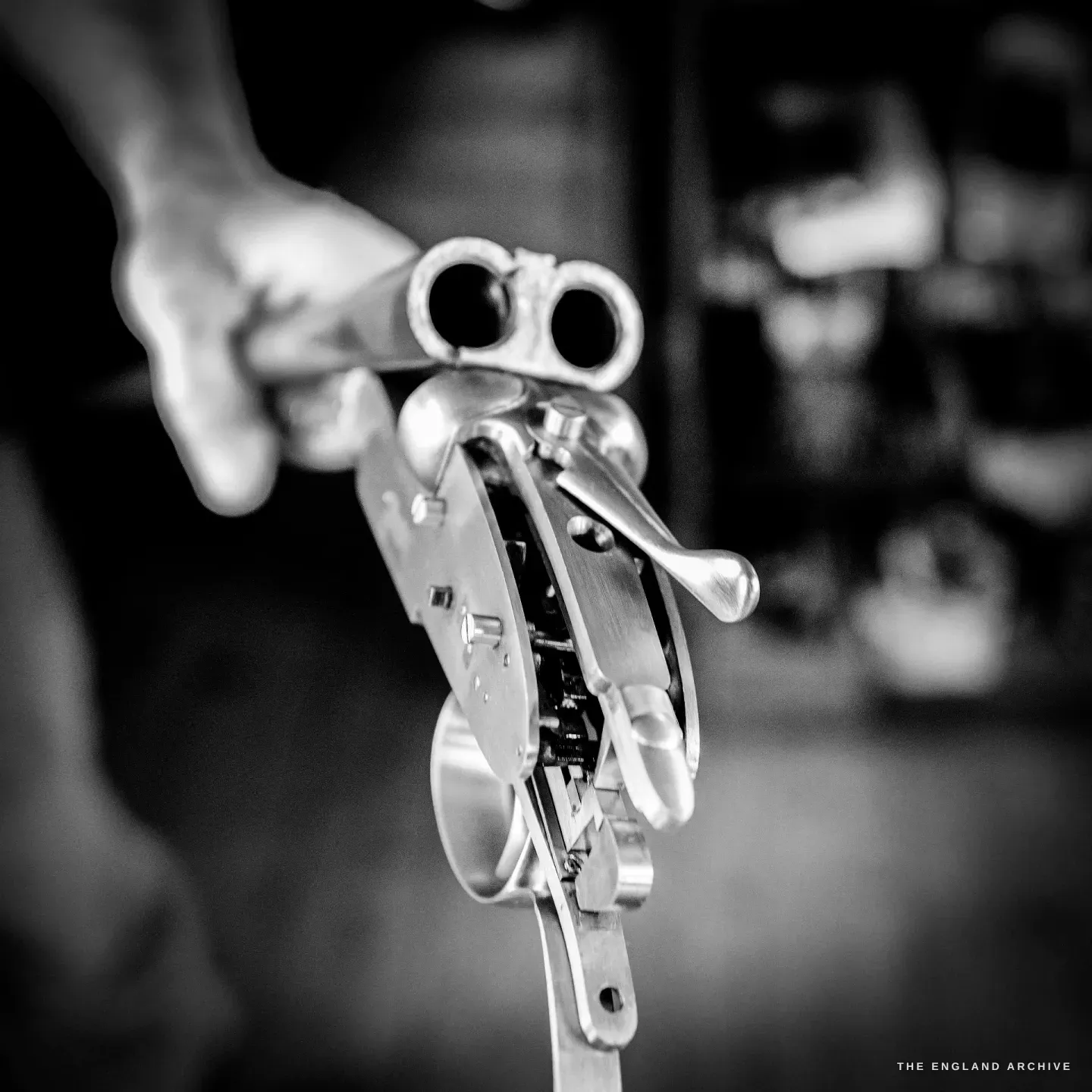 A break-action double gun held open towards the camera, the barrels and the bright fitted lockwork of the action face showing.