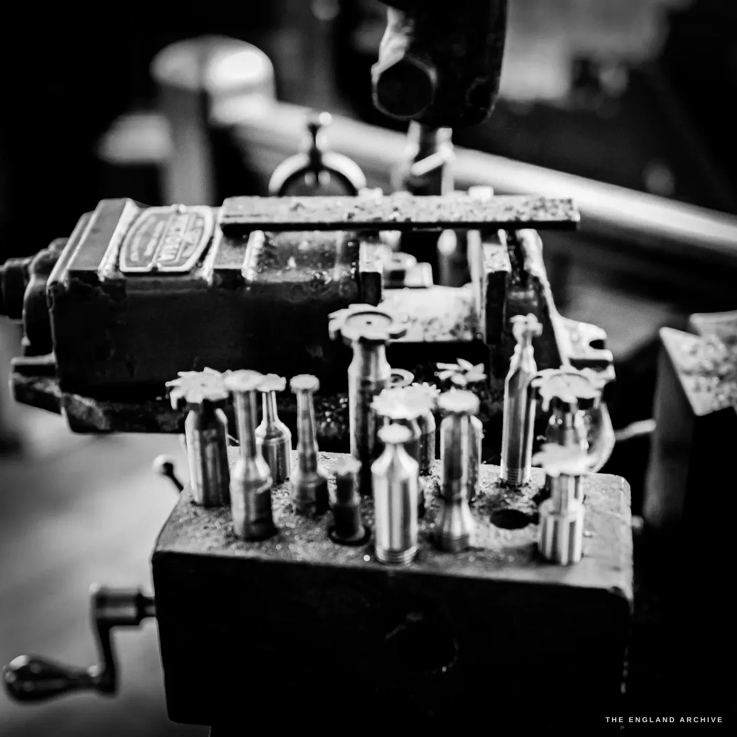 A close study of a machine tool block set with a row of upright cutters and spindles, bright oiled steel against the dark casting.