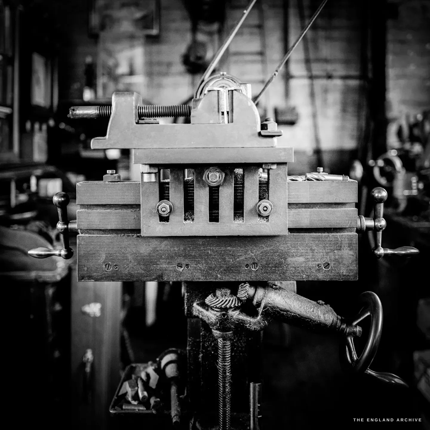 A close study of a machine vice and its screw, the jaws and handwheel bright with use, the mechanism dark behind.