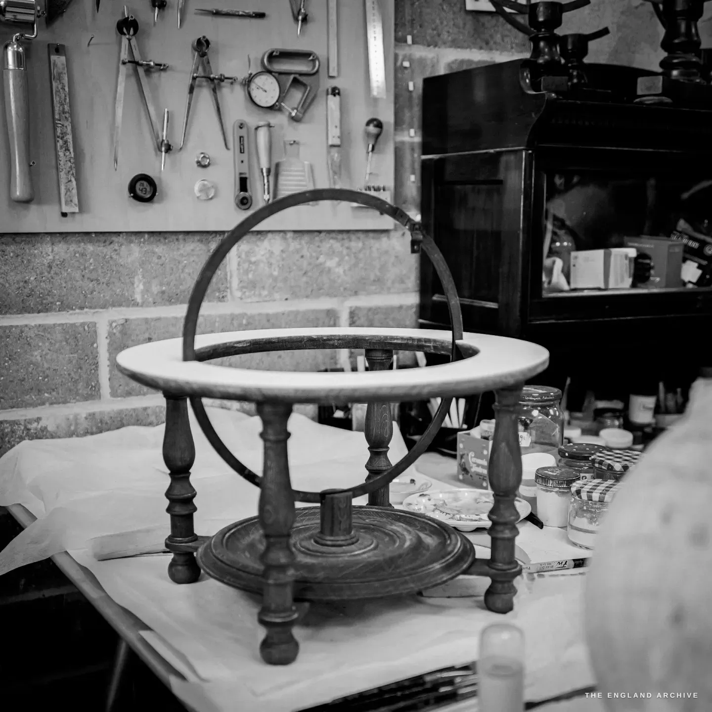 An empty globe stand on the bench - turned wooden legs, a wooden horizon ring and a brass meridian circle - waiting for its globe.