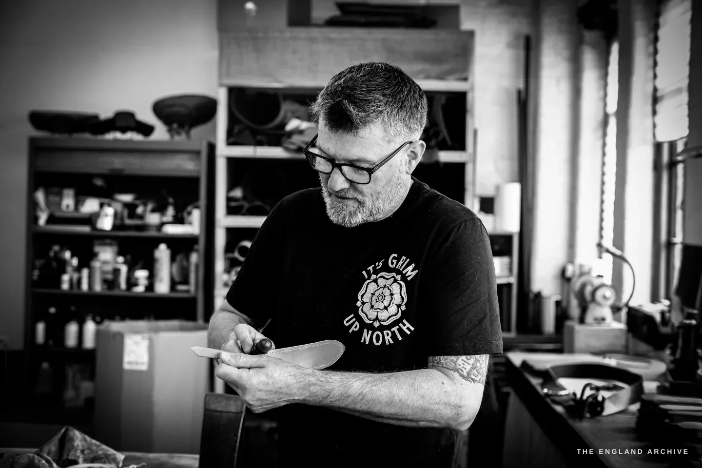 Kevin Wilebore, bearded and in glasses and an It&rsquo;s Grim Up North t-shirt, holds a pale curved template at the bench.