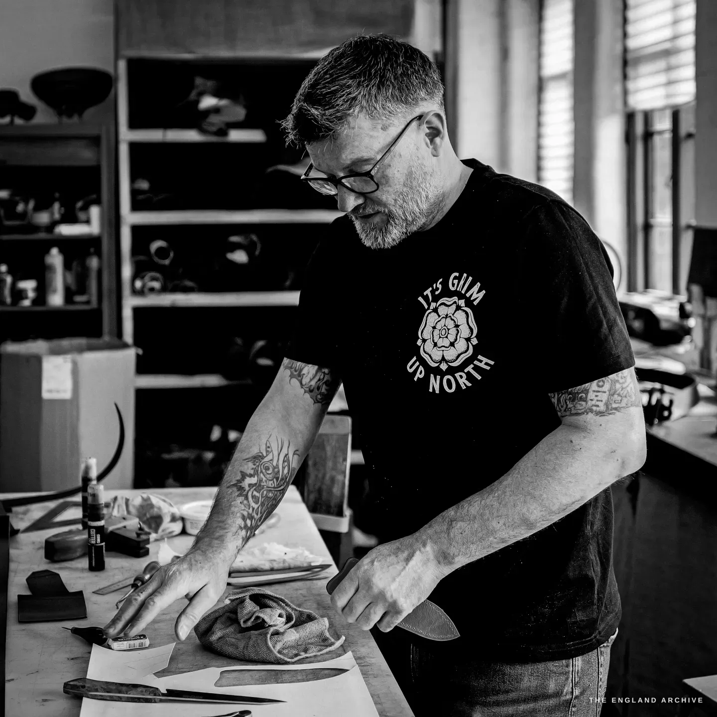 Kevin Wilebore works a small wet-formed piece of leather at the bench in his It&rsquo;s Grim Up North t-shirt.