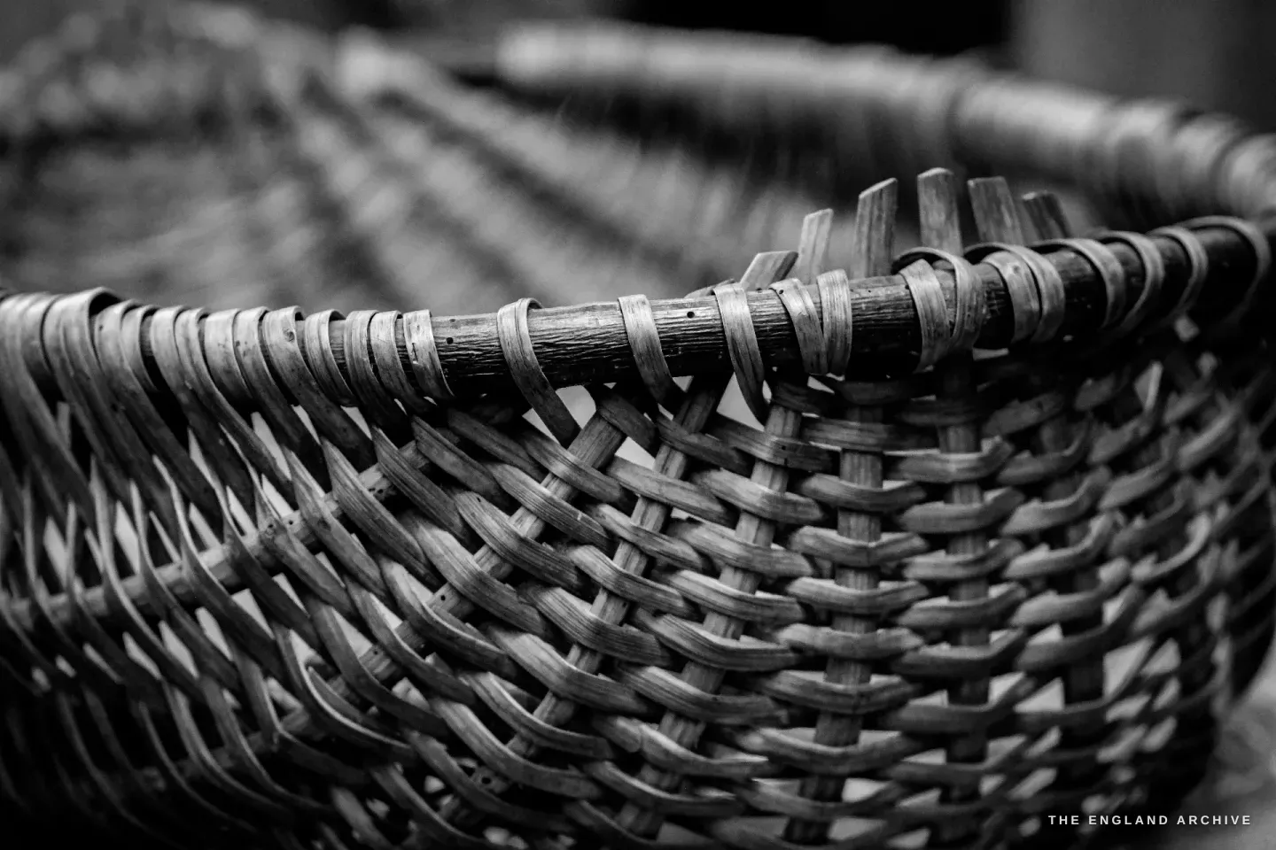 Close-up of the rim of a finished Whisket basket, the rod bow of the handle bound to the rim by a tight wrapping of fine splint.