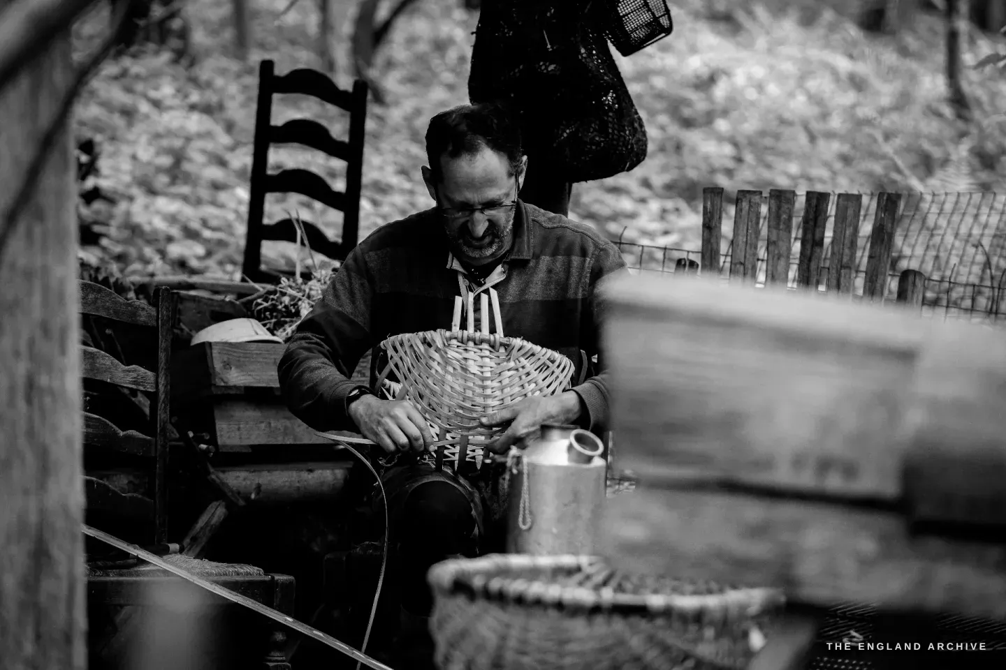 Lewis caught mid-laugh at the workbench, a basket-in-progress on his lap, the Kelly Kettle steaming beside him.