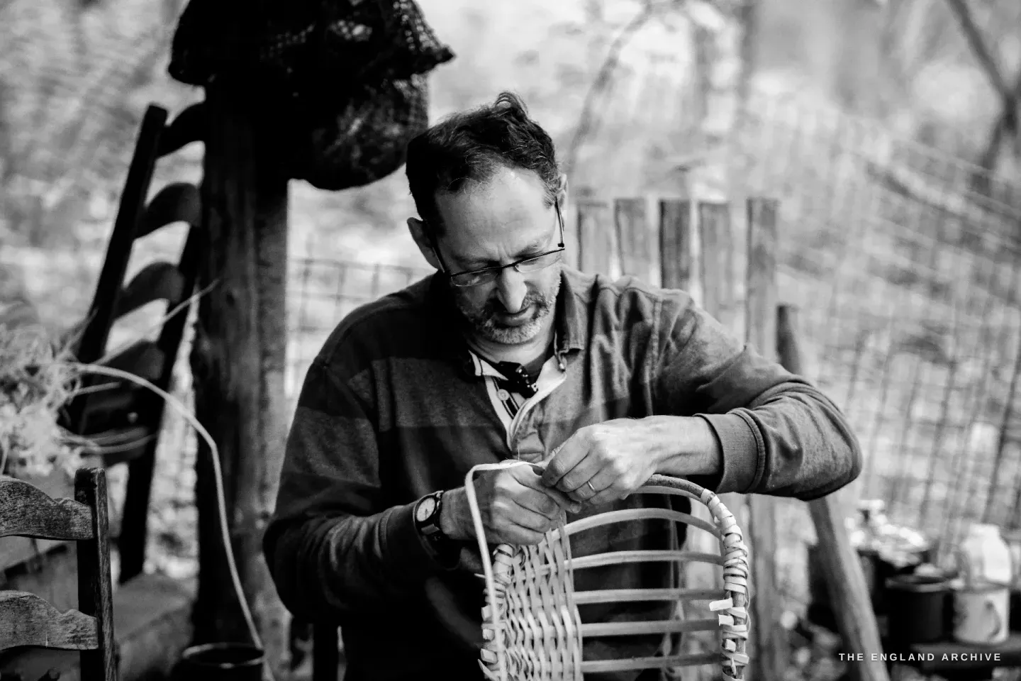 Lewis bowed over the basket on his lap, both hands threading a splint into the weave.