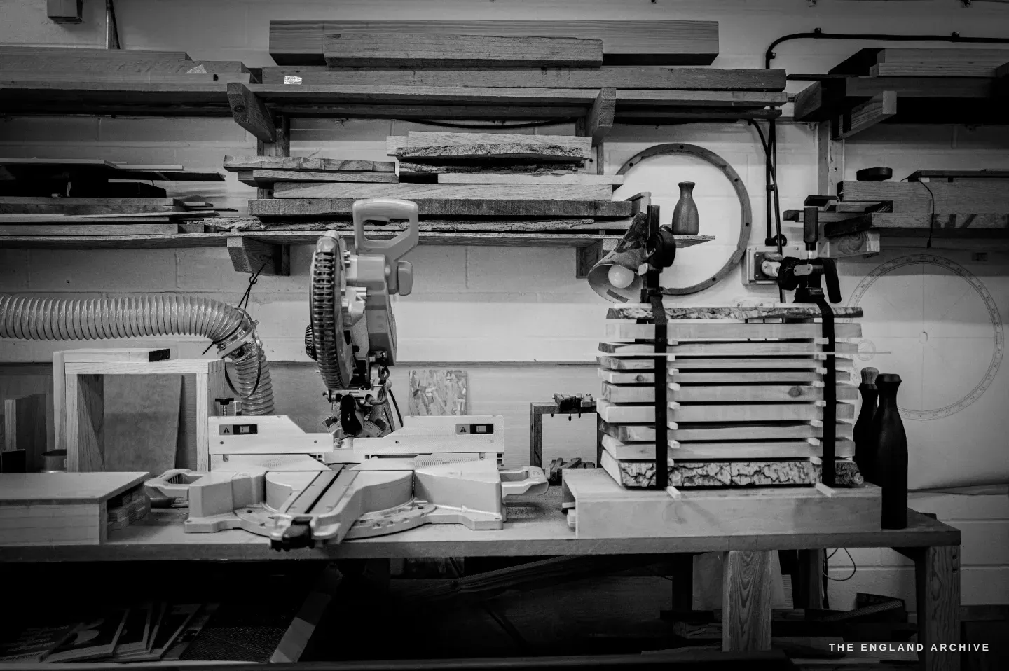 Louis&rsquo;s woodworking bench: a mitre saw, racked timber, and a turned wooden vessel.