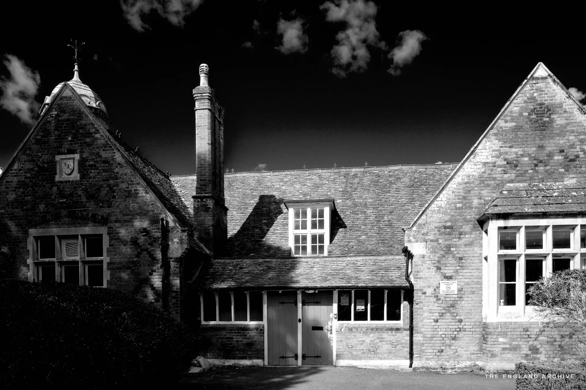 Victorian red-brick school building with red double doors and a central bell turret, Long Melford.