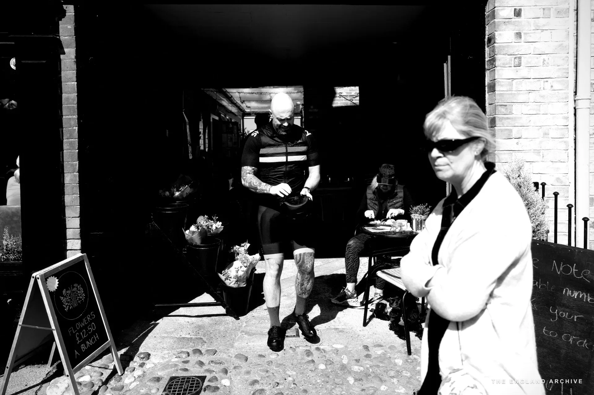 Julie Thomson standing beside a red K6 telephone box marked 'Walkers Hub', holding a blue folder and a red bag.