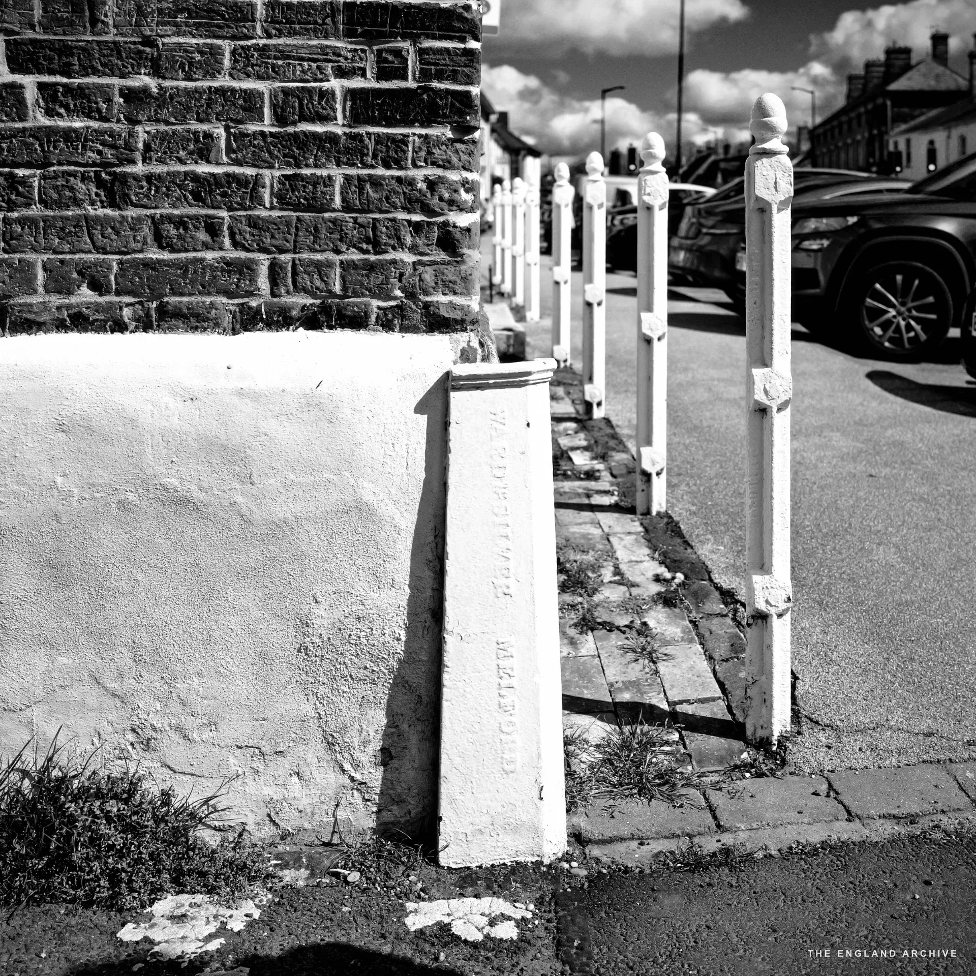 A cast-iron wall protector mounted at the corner of a Long Melford building, marked with the maker’s name Ward & Silver, Iron Founders.