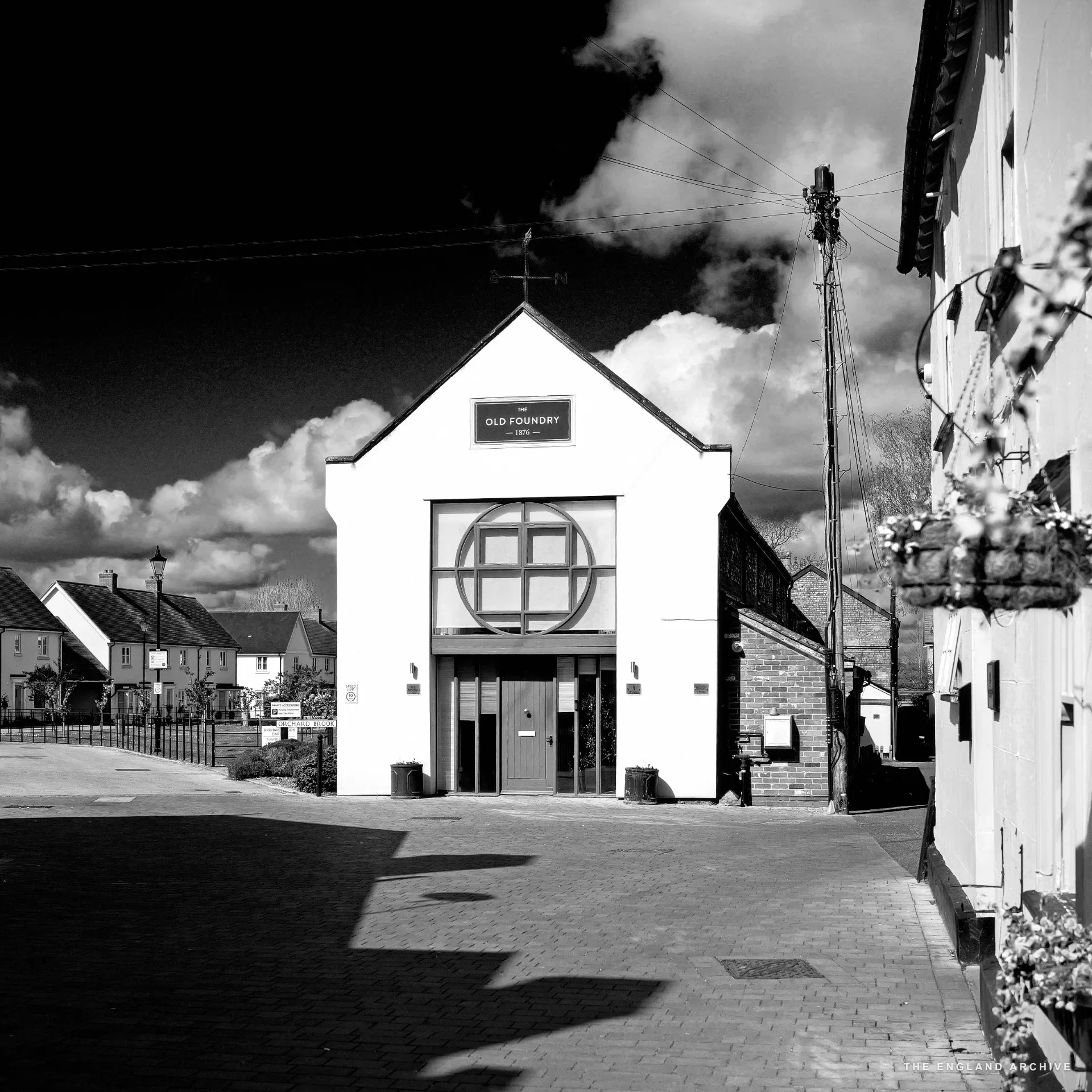 'The Old Foundry', a cream-painted building with a prominent circular foundry-wheel motif and red double doors over a cobbled driveway.
