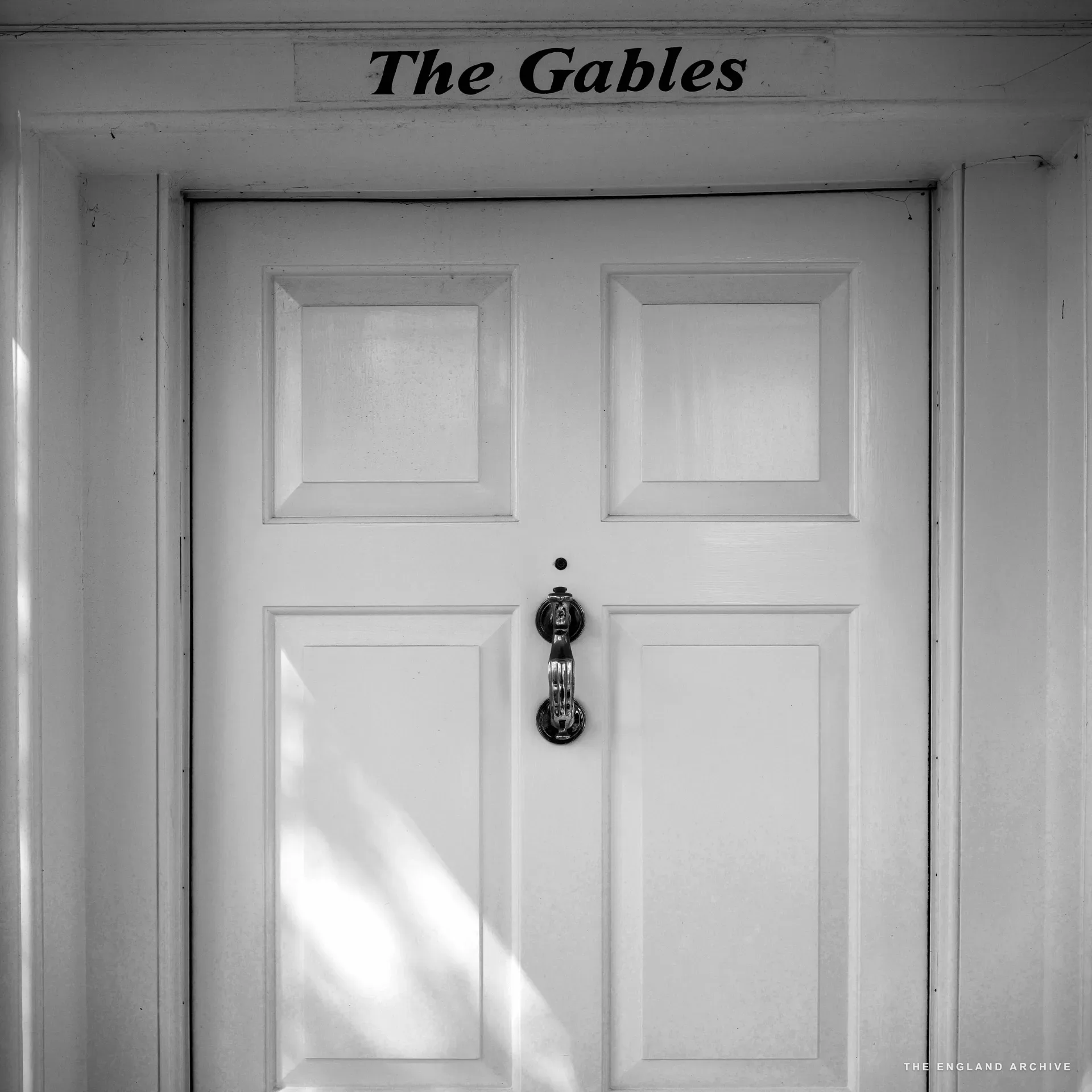 A white-panelled Georgian front door titled 'The Gables' with a brass urn knocker.