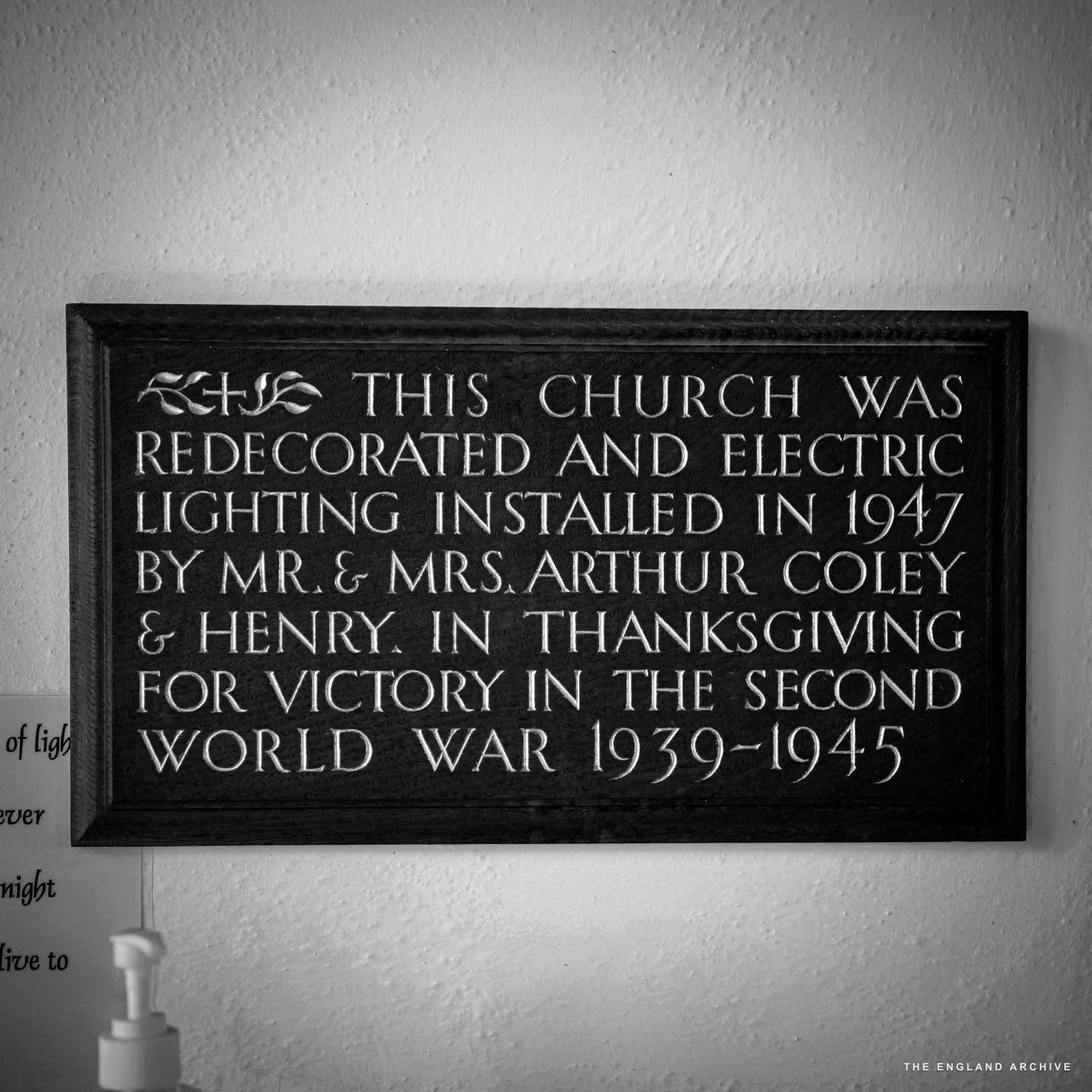 A carved wooden plaque reading 'This church was redecorated and electric lighting installed in 1947 by Mr and Mrs Arthur Coley and Henry'.