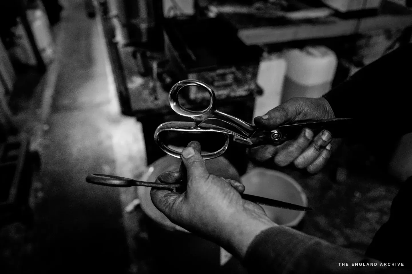 Neil’s hands holding a bright bow-handled pair of scissors and a separate loose blade, showing how the two halves come together.