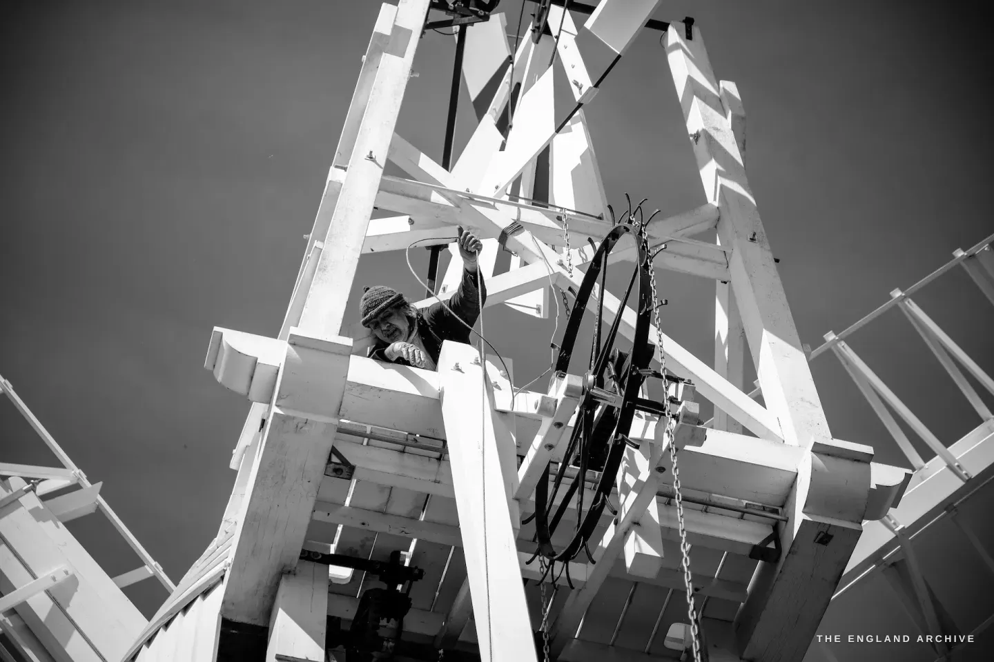 Paul Kemp at the top of the mill working at the brake wheel, shot from below through the white-painted timber framework