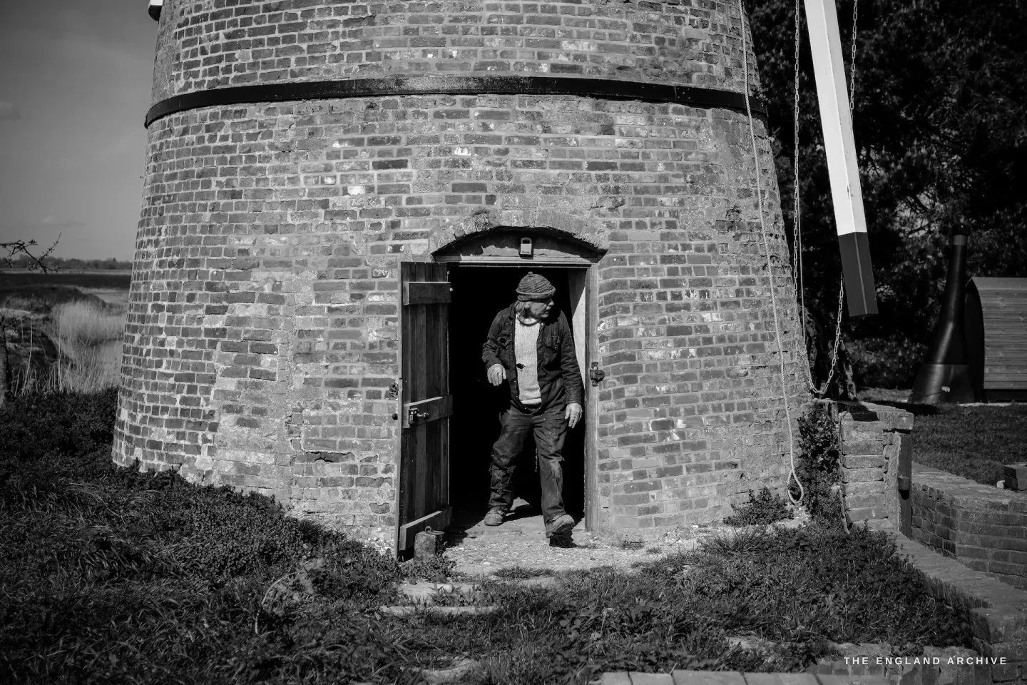 Paul Kemp stepping out of the mill doorway, ducking slightly under the arched brick entrance