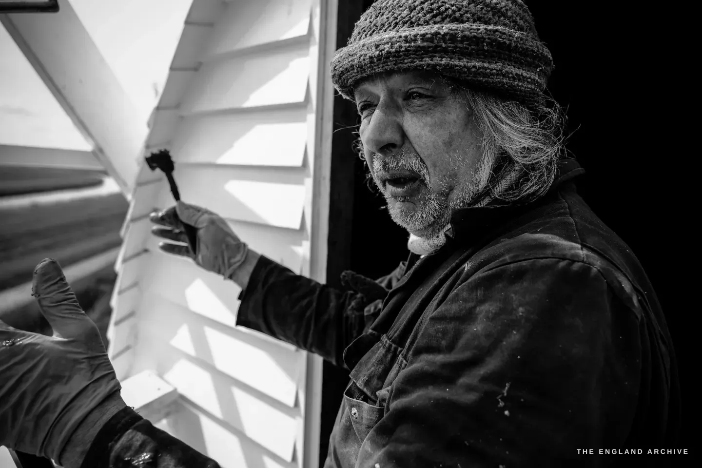 Paul adjusting the sail shutters at the cap, close-up of his hands working the mechanism