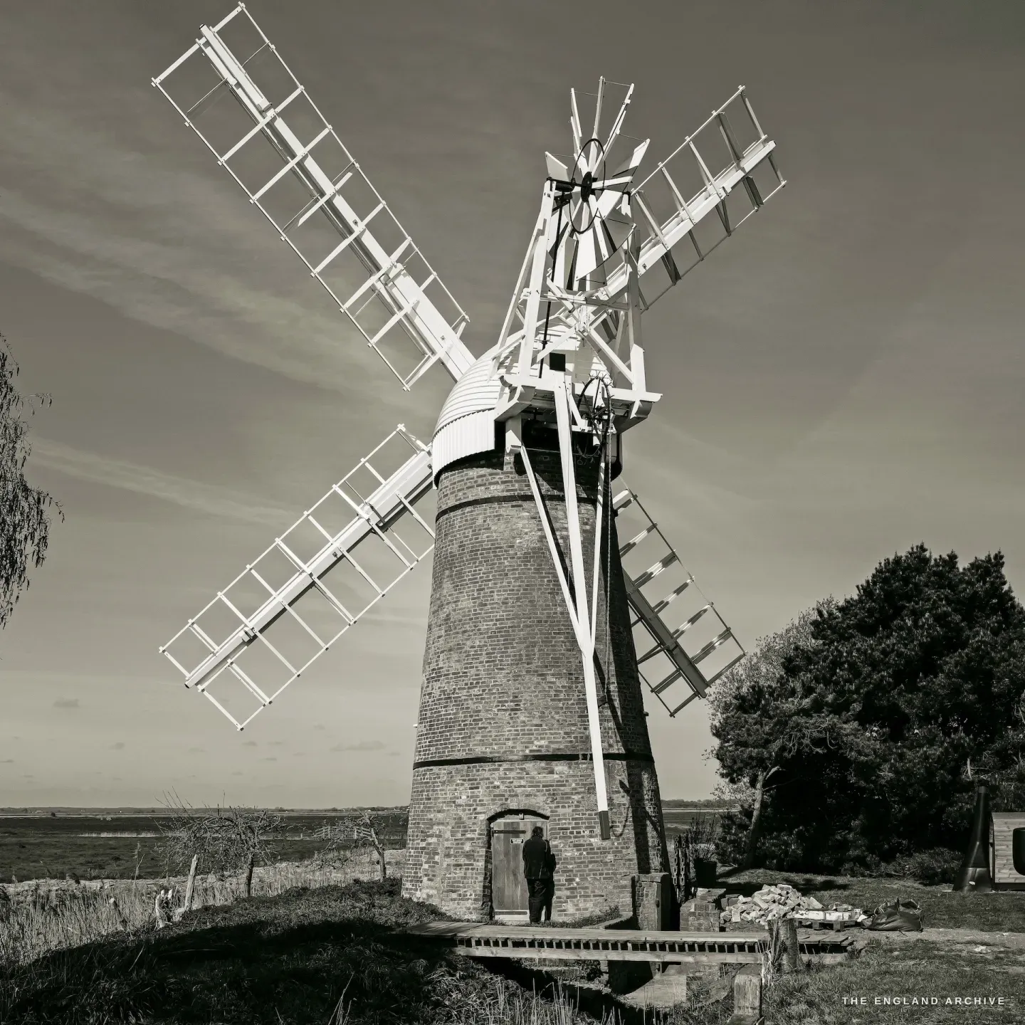 The full mill with Paul’s small figure standing at the doorway, sails spread wide, the scale of the building evident