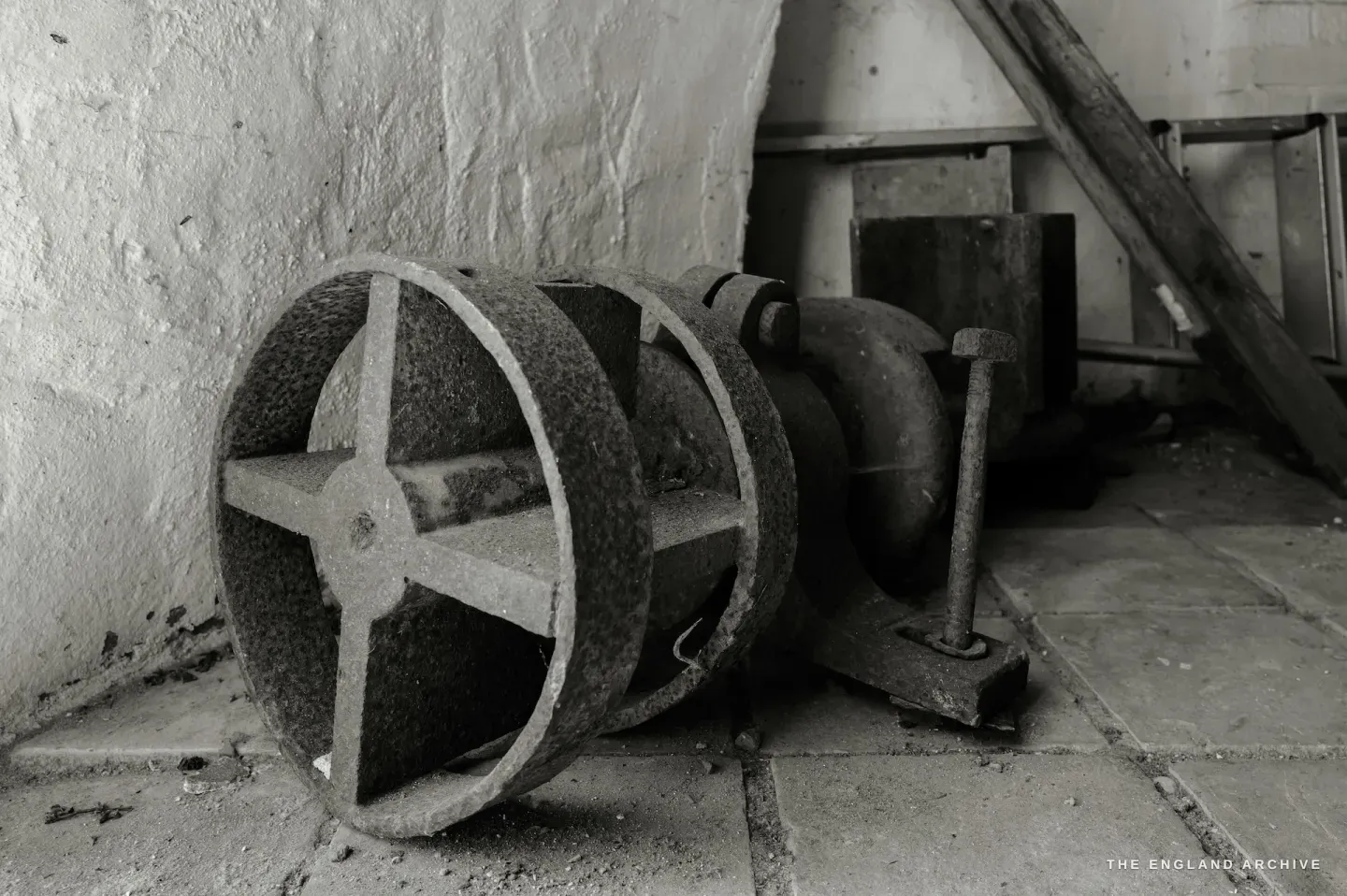 A cast iron cylinder roller lying on the floor inside the mill, heavy and worn