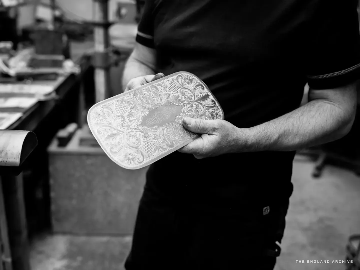 Phil holding a rectangular tray blank deeply embossed with floral repousse around a blank central cartouche.