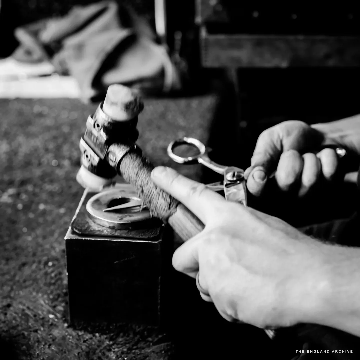 Sam hammering a part-made pair of scissors over a small bick, both hands at the work, the steel held against the curve of the stake.