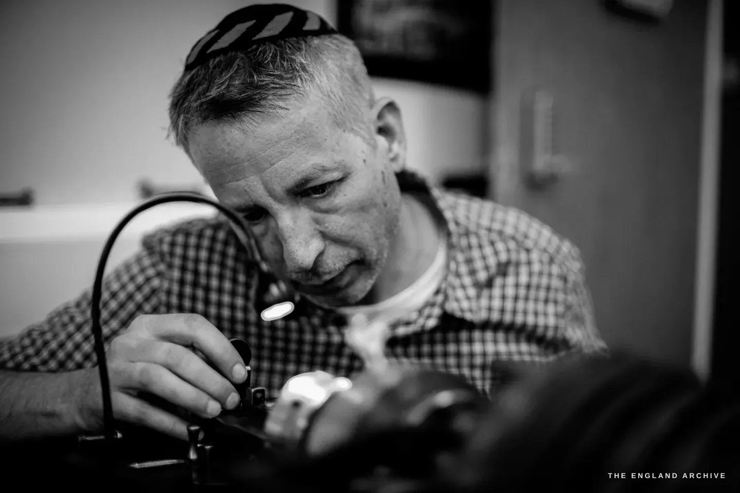 A close portrait of Seth Kennedy bending into a loupe at the bench, concentrating.