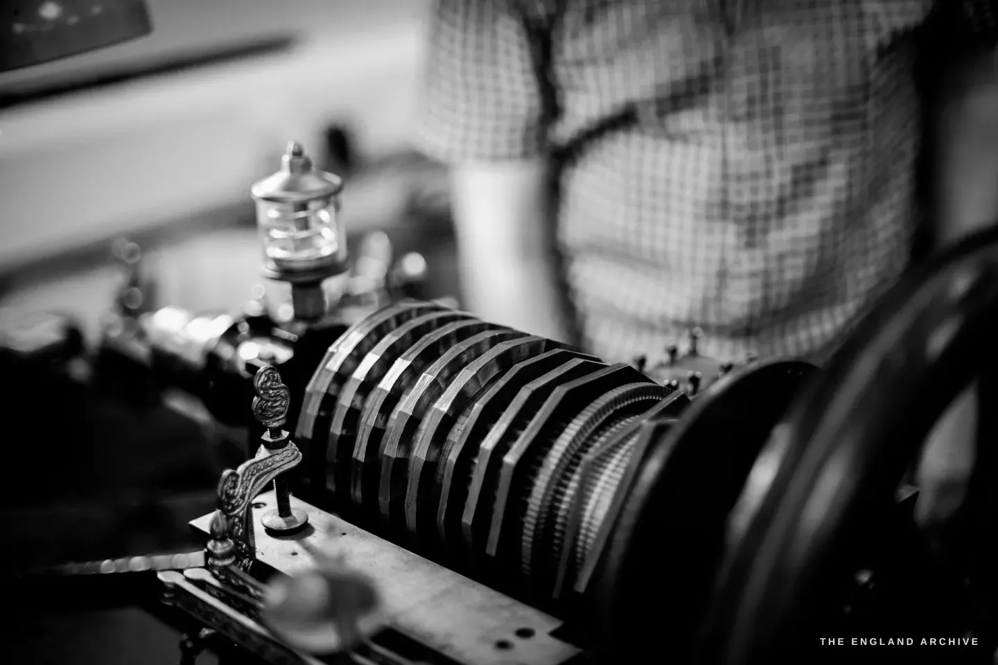The rose engine rosette stack seen from the side, Seth Kennedy’s torso blurred behind it.
