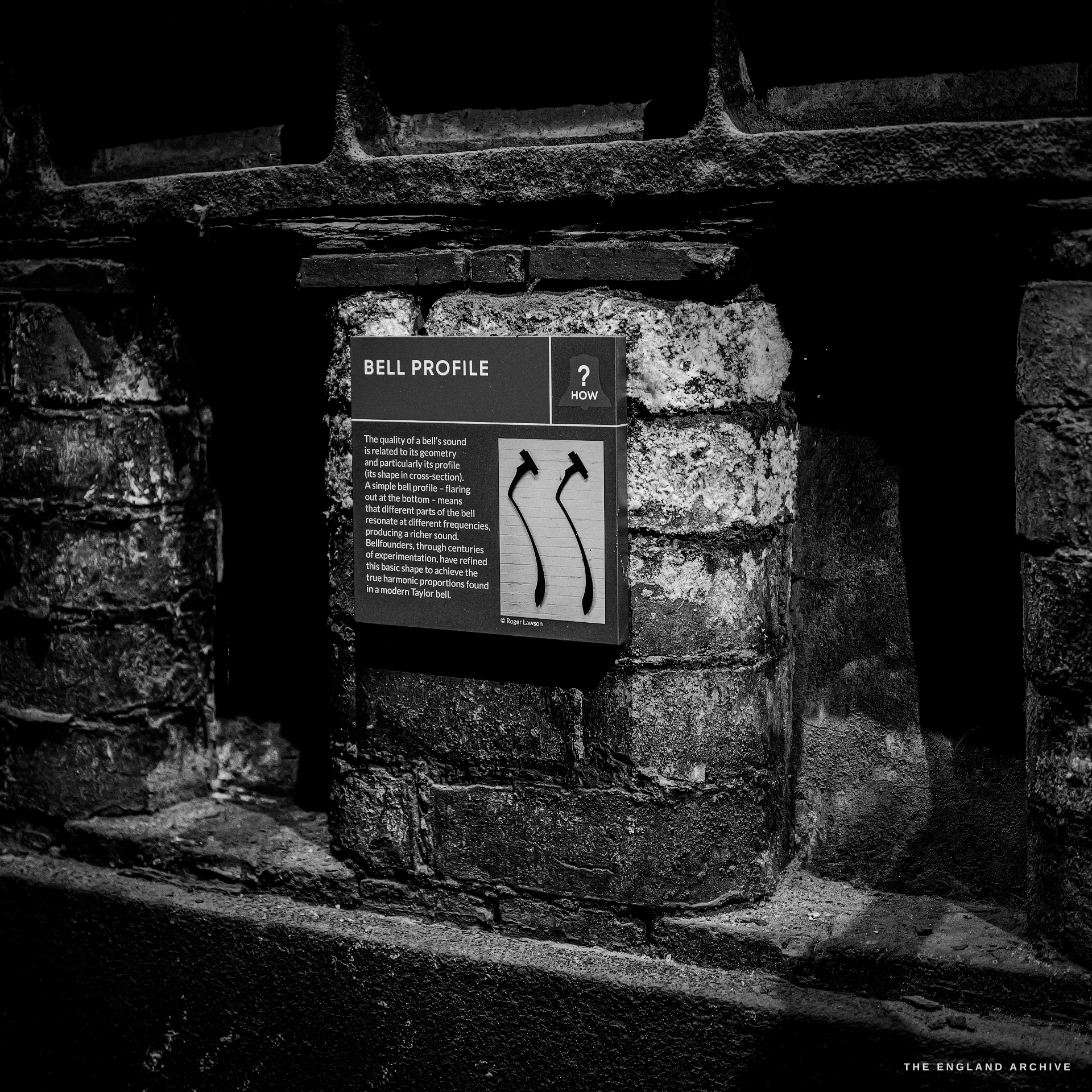 An interpretation panel headed BELL PROFILE mounted on a rough brick pier, with a diagram of two bell-section curves.