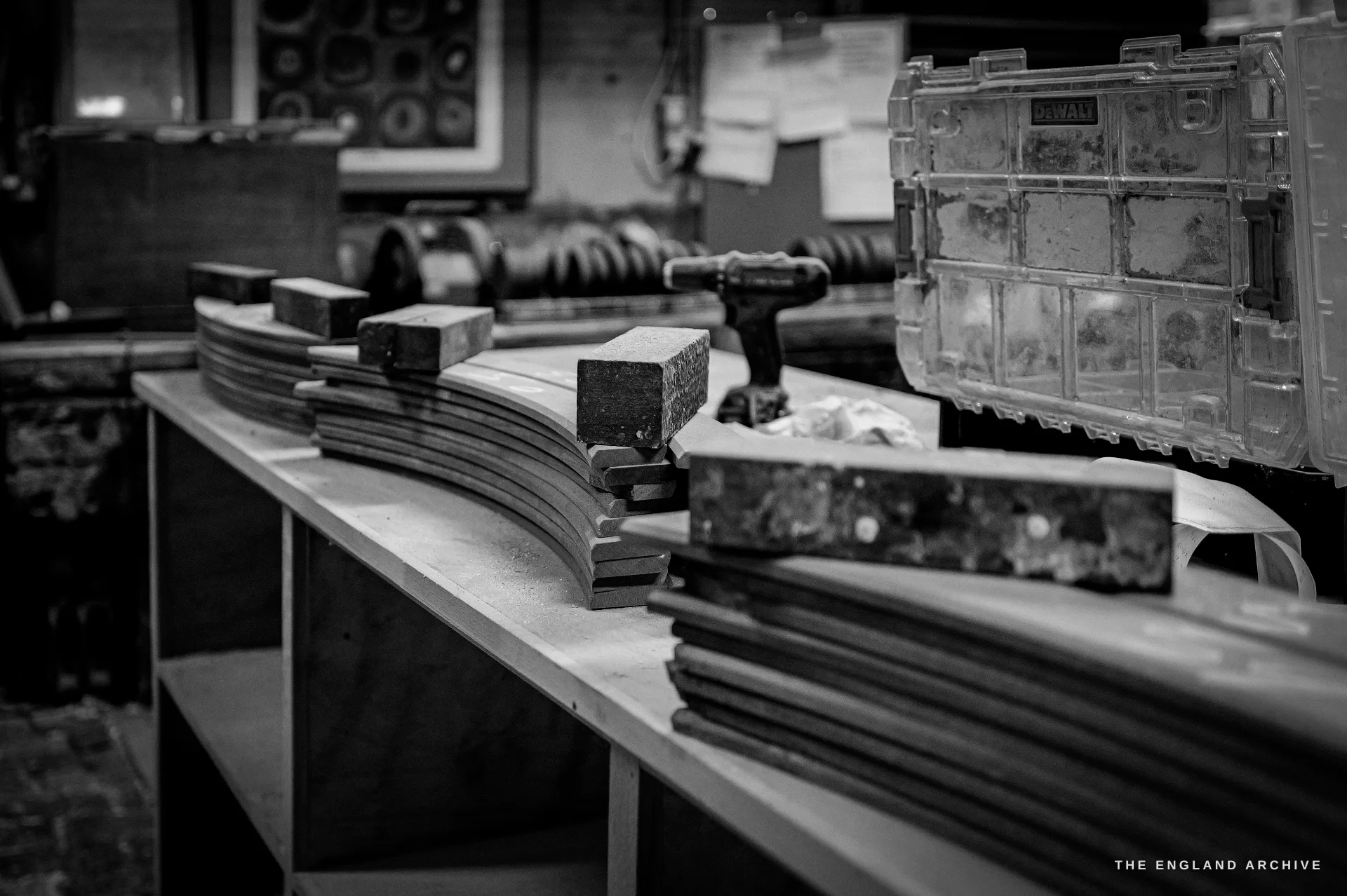 Curved wooden strickle boards - the templates that sweep a bell profile into the mould - laid out on a workbench, framed prints on the wall behind.