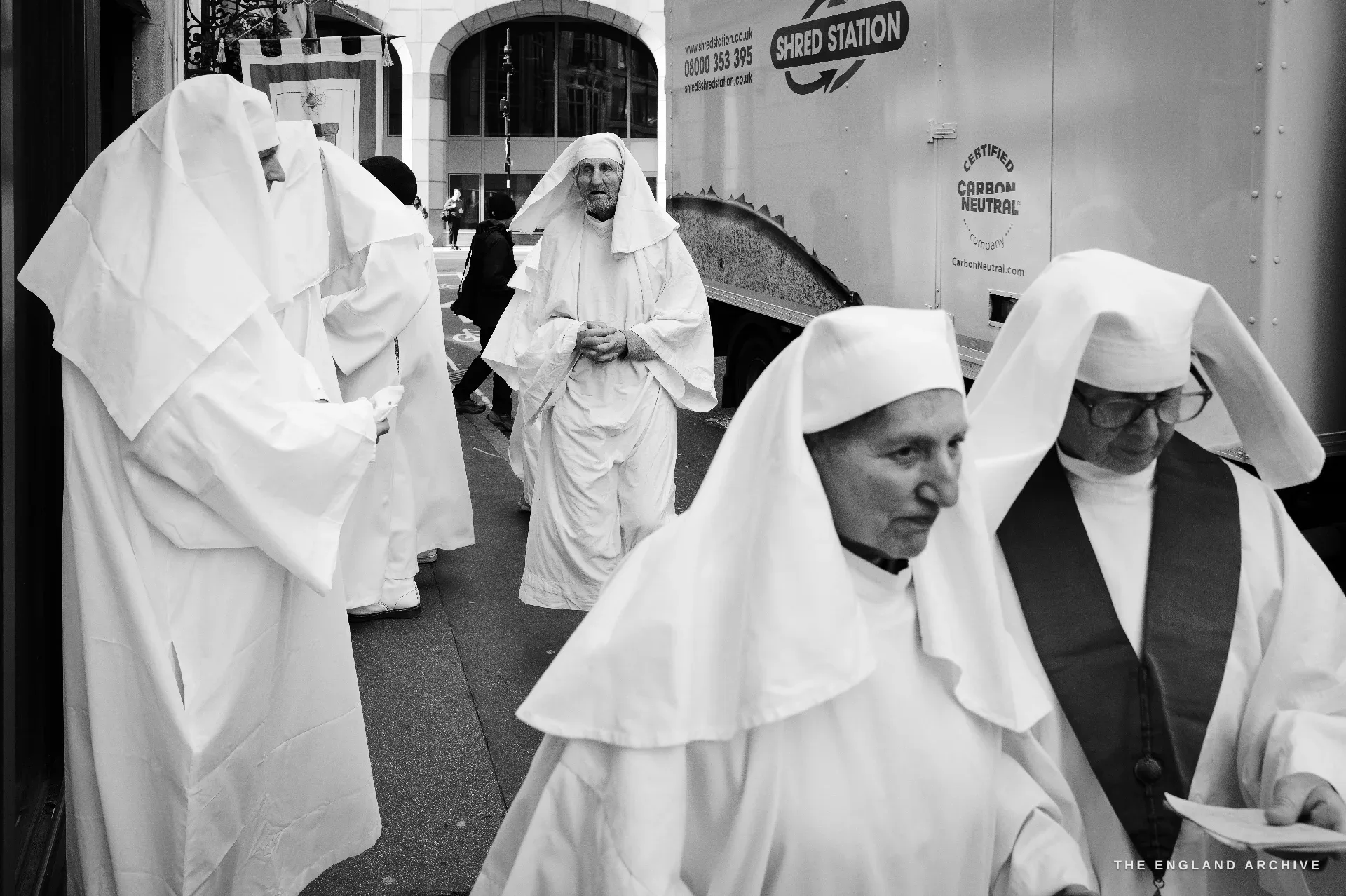 Druid Order members in white robes crossing the City of London street toward Tower Hill
