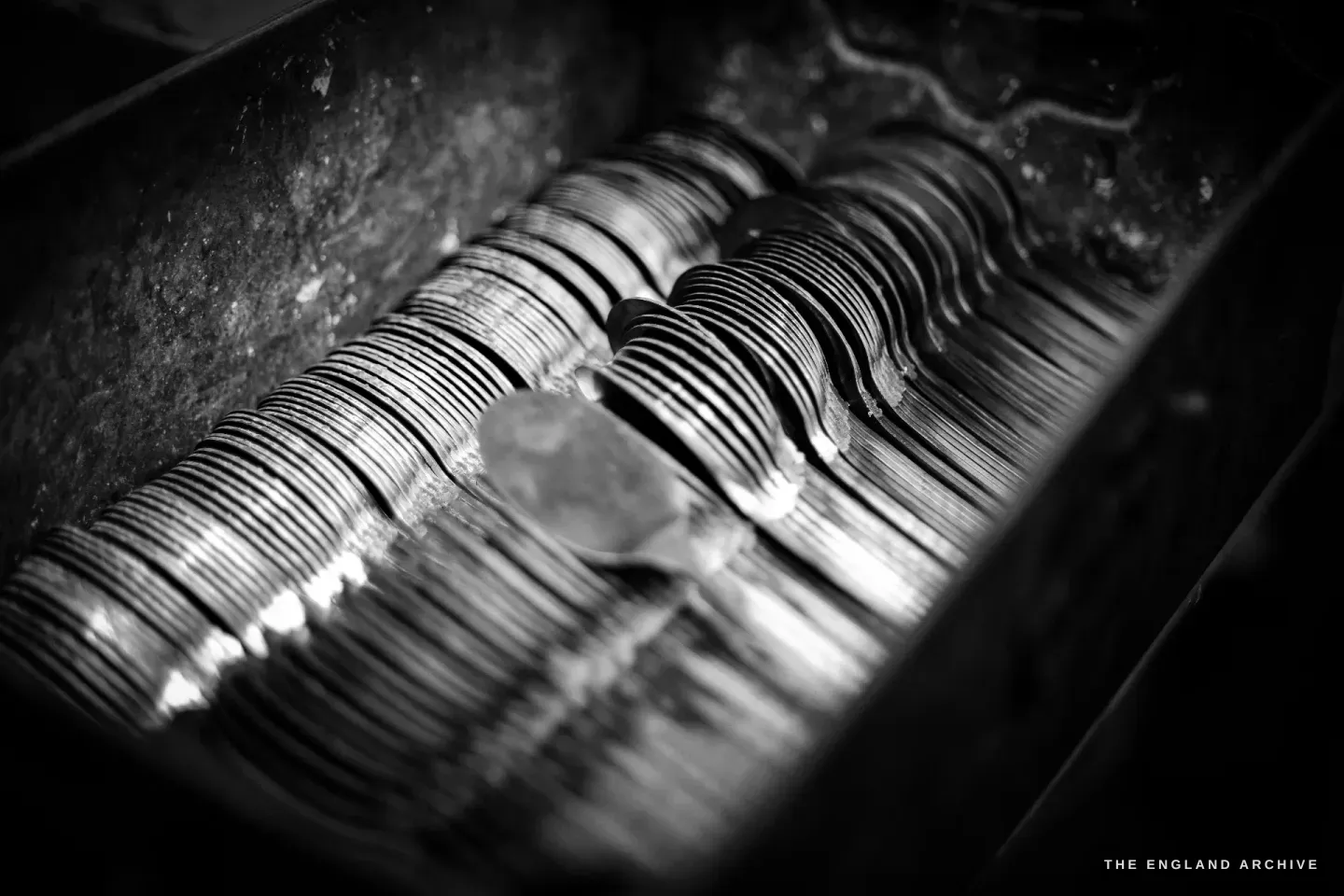 A steel bin packed with a long row of part-finished fork blanks stacked on edge.