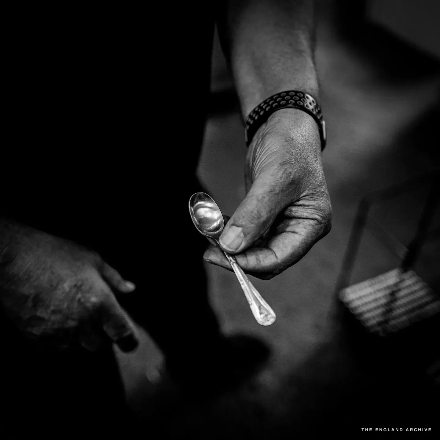 Stephen Wright’s hand holding up a small finished teaspoon with a patterned handle.