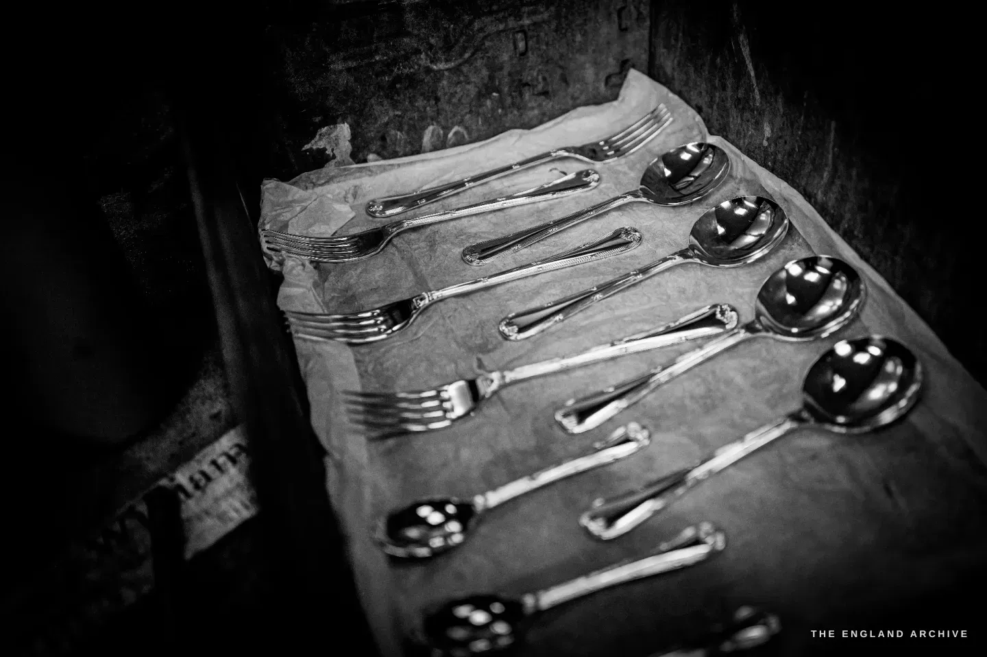 A finished set of silver forks and round soup spoons with patterned handles, laid out on tissue paper in a box.