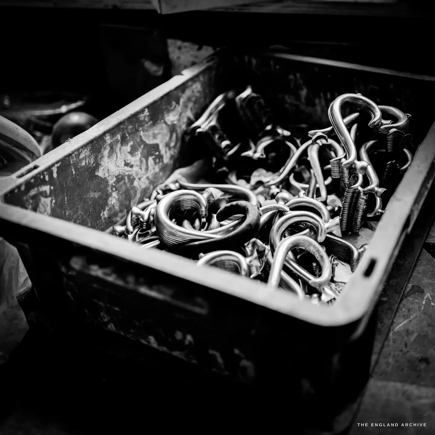 A grimy bin full of cast scrolled handles waiting to be assembled.