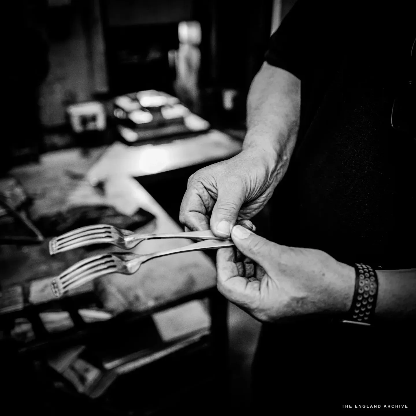 Stephen Wright’s hands comparing two part-made forks against each other, checking them at the bench.