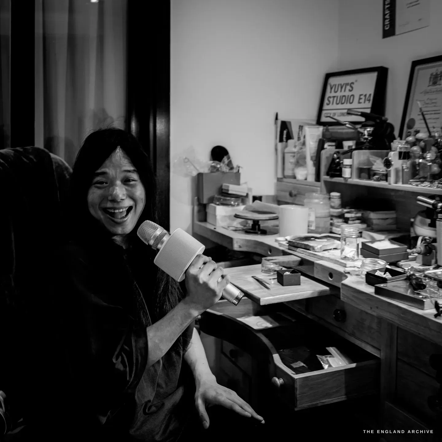 Yuyi laughing, holding a small microphone to her face as I recorded the interview, the "Yuyi’s Studio E14" sign behind her.