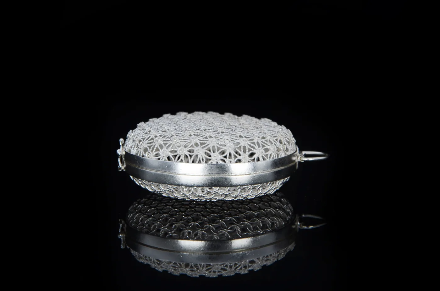 A second view of the openwork filigree silver box, the wirework catching the light.