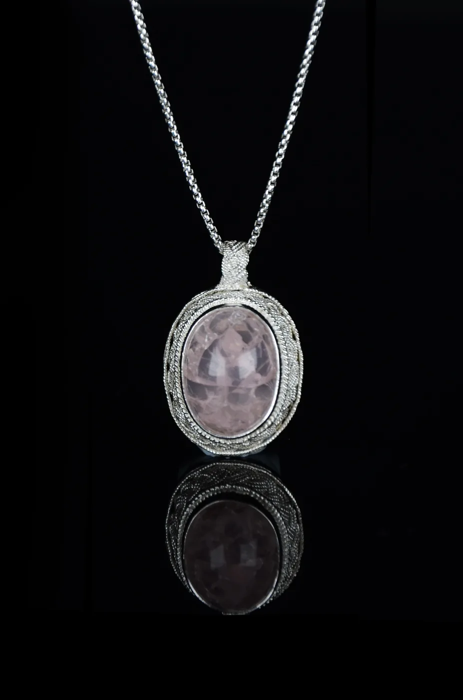 A filigree waving pendant of fine silver openwork on a chain.