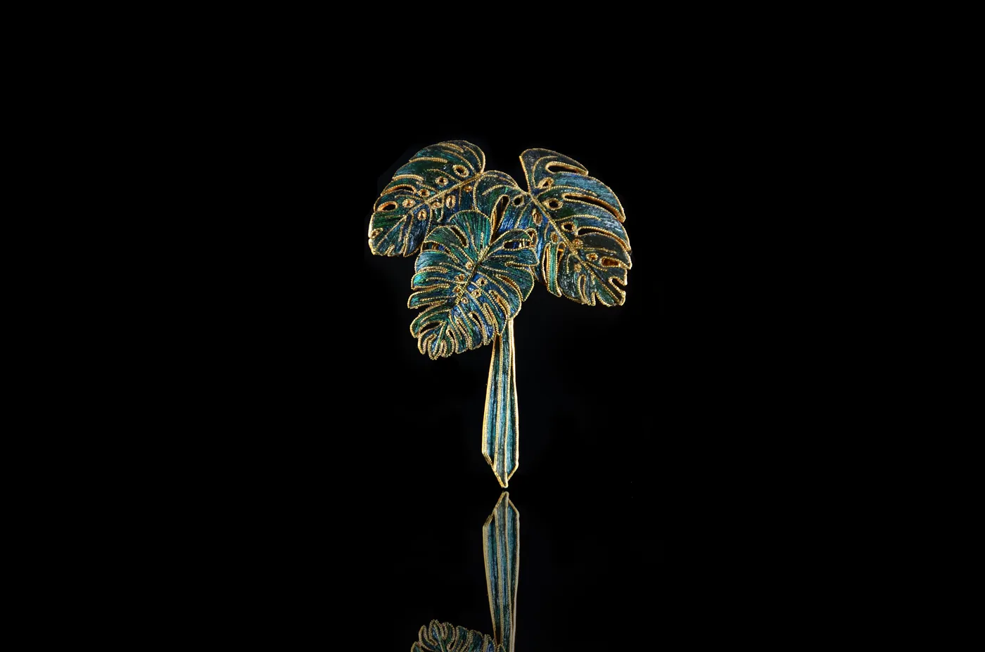 A detail of the monstera leaf brooch, the green feather inlay set into gold cells.