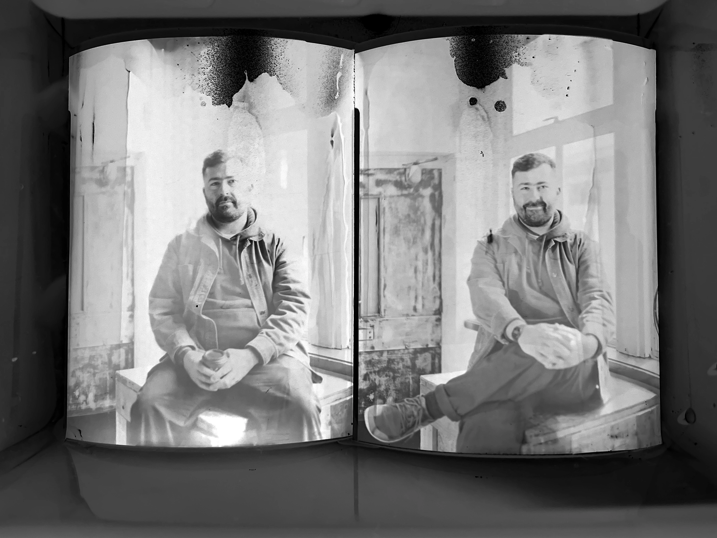 Two large format portraits in a developing tray - the tonal range visible across both prints as the image emerges