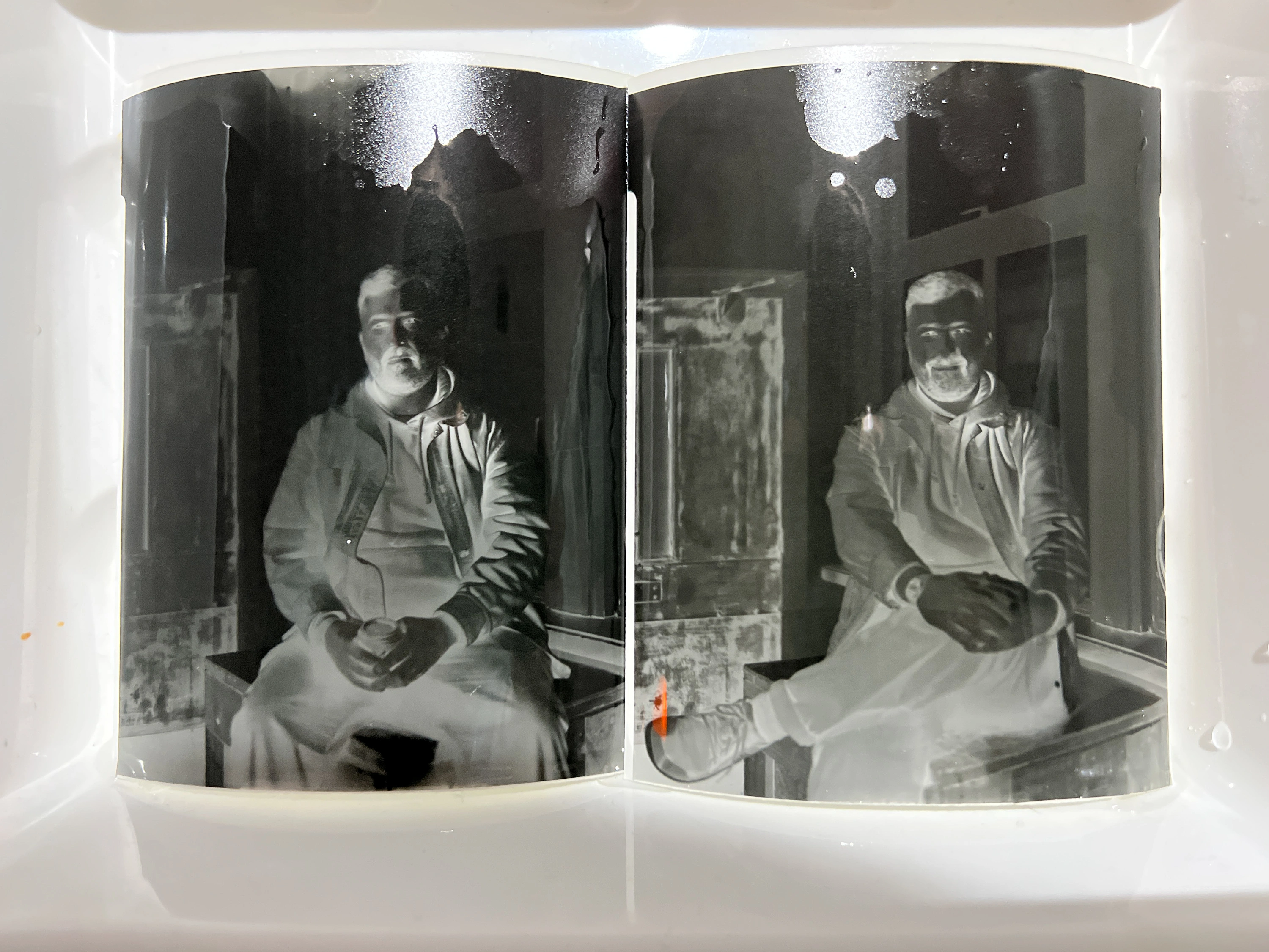 Film negatives in the developing tray - the chemical process that turns latent light into a visible image