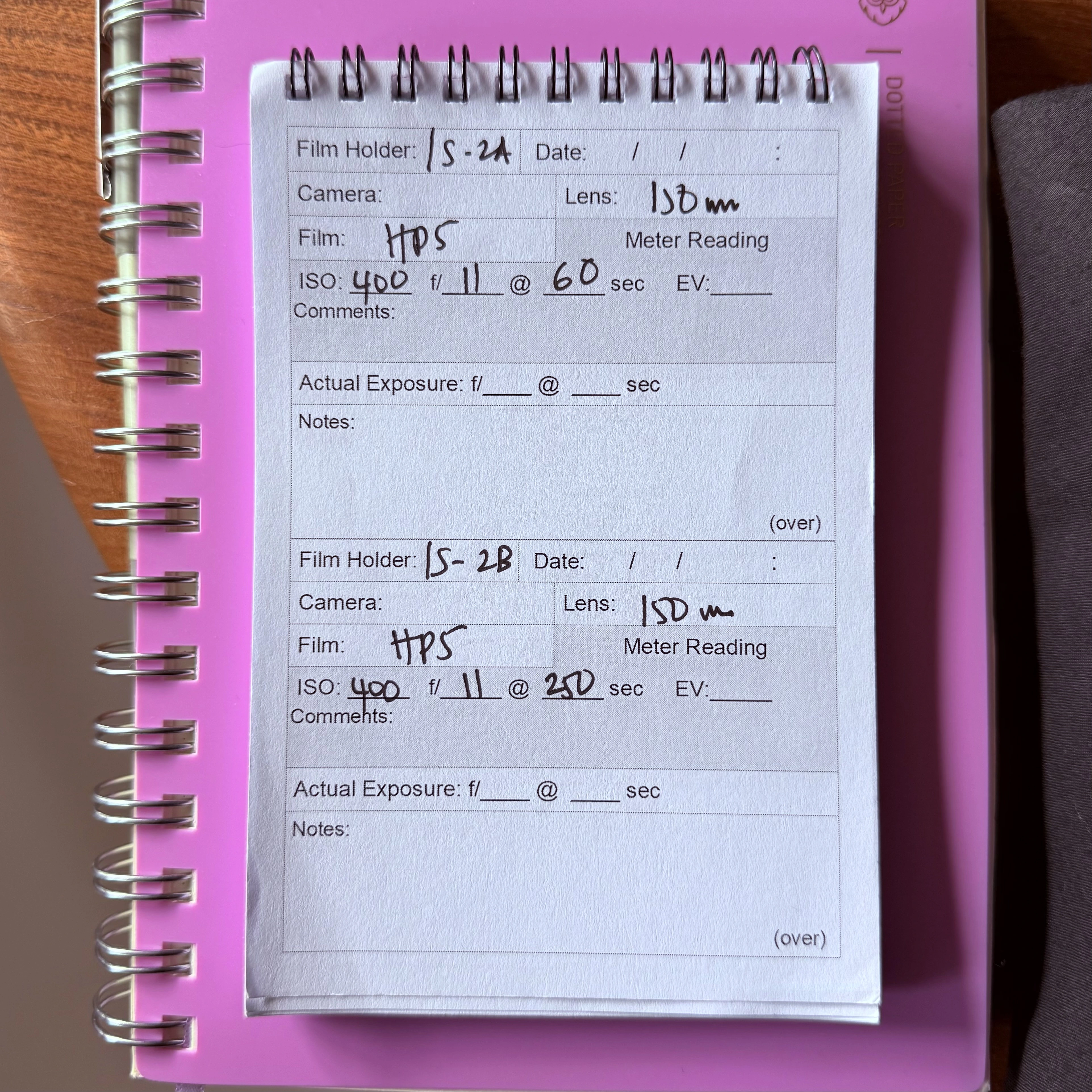 Exposure log notebook showing handwritten entries for two sheets of HP5 film at ISO 400, shot on a 150mm lens at f/11