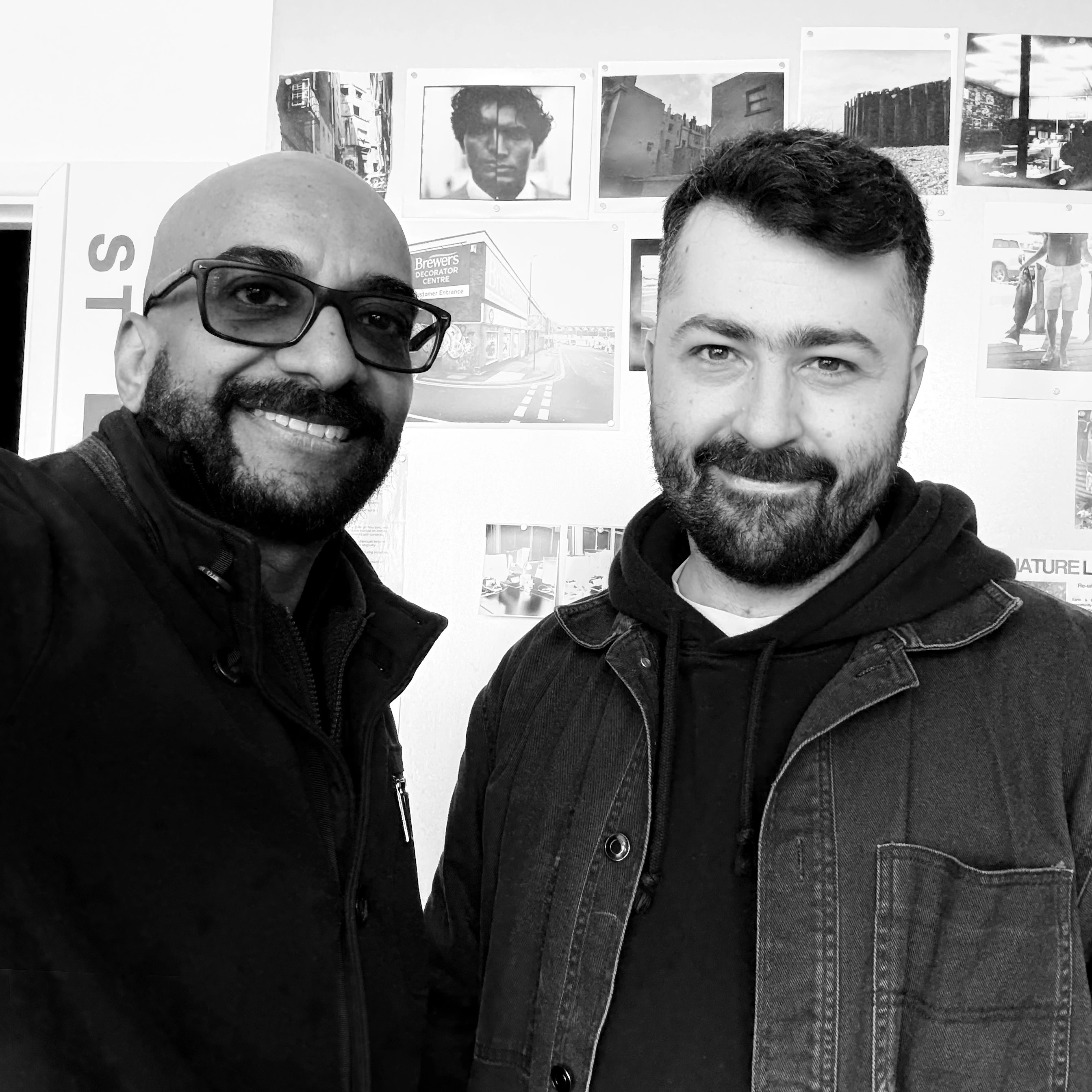 Mash Bonigala and Josh Redfearn standing together at the POST in Hove, with black and white photographs pinned to the wall behind them